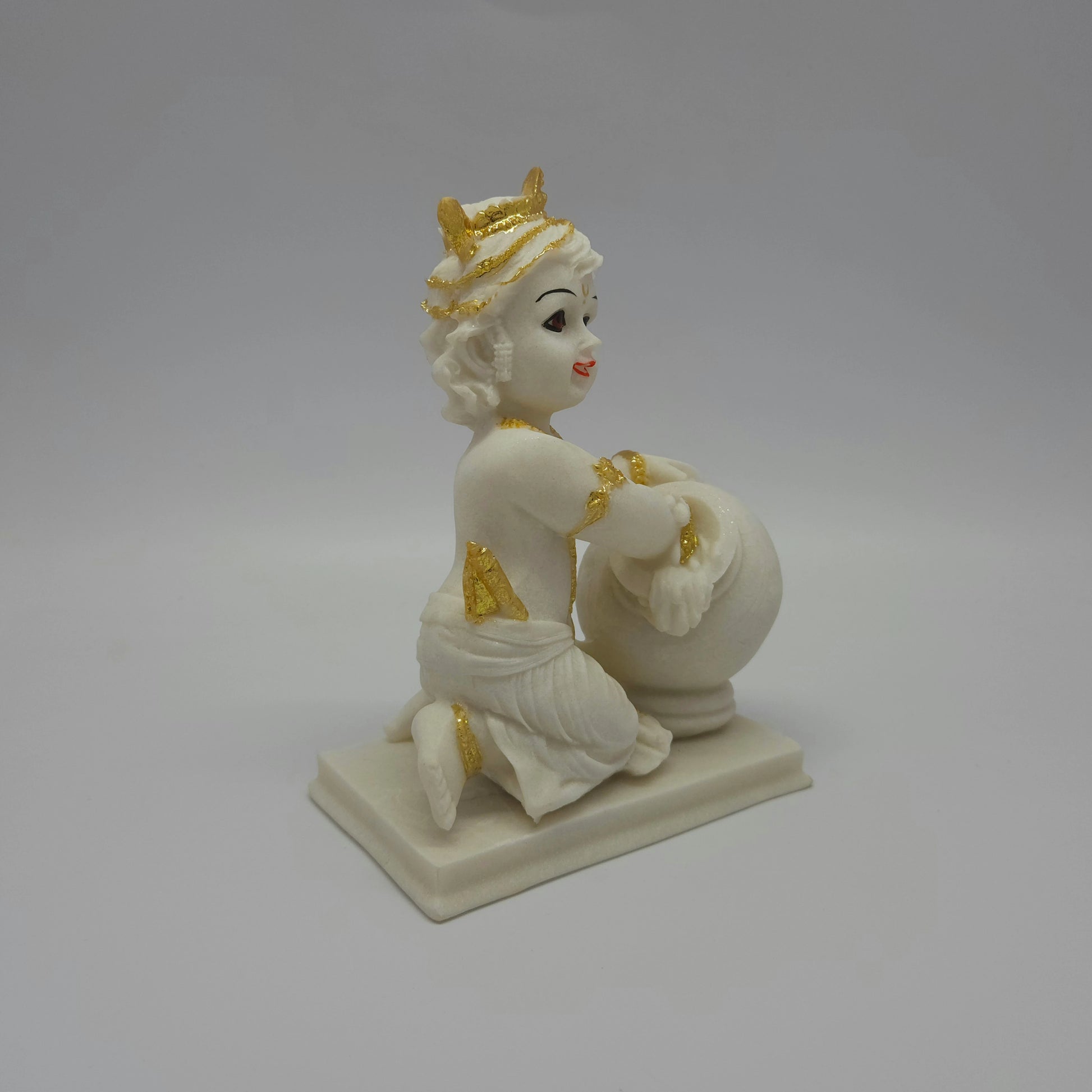 Right perspective view of the white resin child Krishna figurine showcasing the hand-set gold paint accents on the butter jar and clothing.