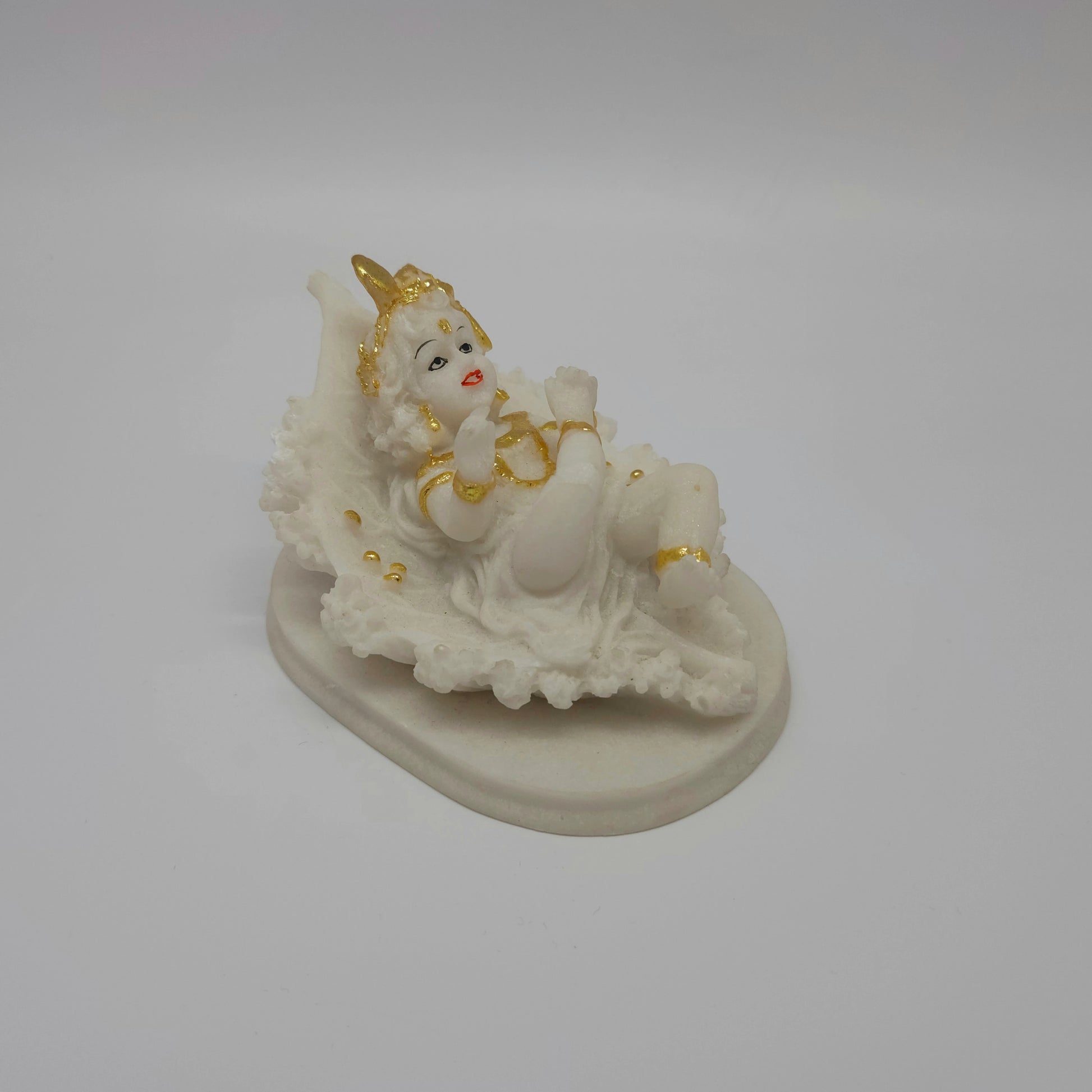 Angled back right look of the white poly-marble child Krishna figurine showcasing the smooth texture and the gold highlights on his crown.