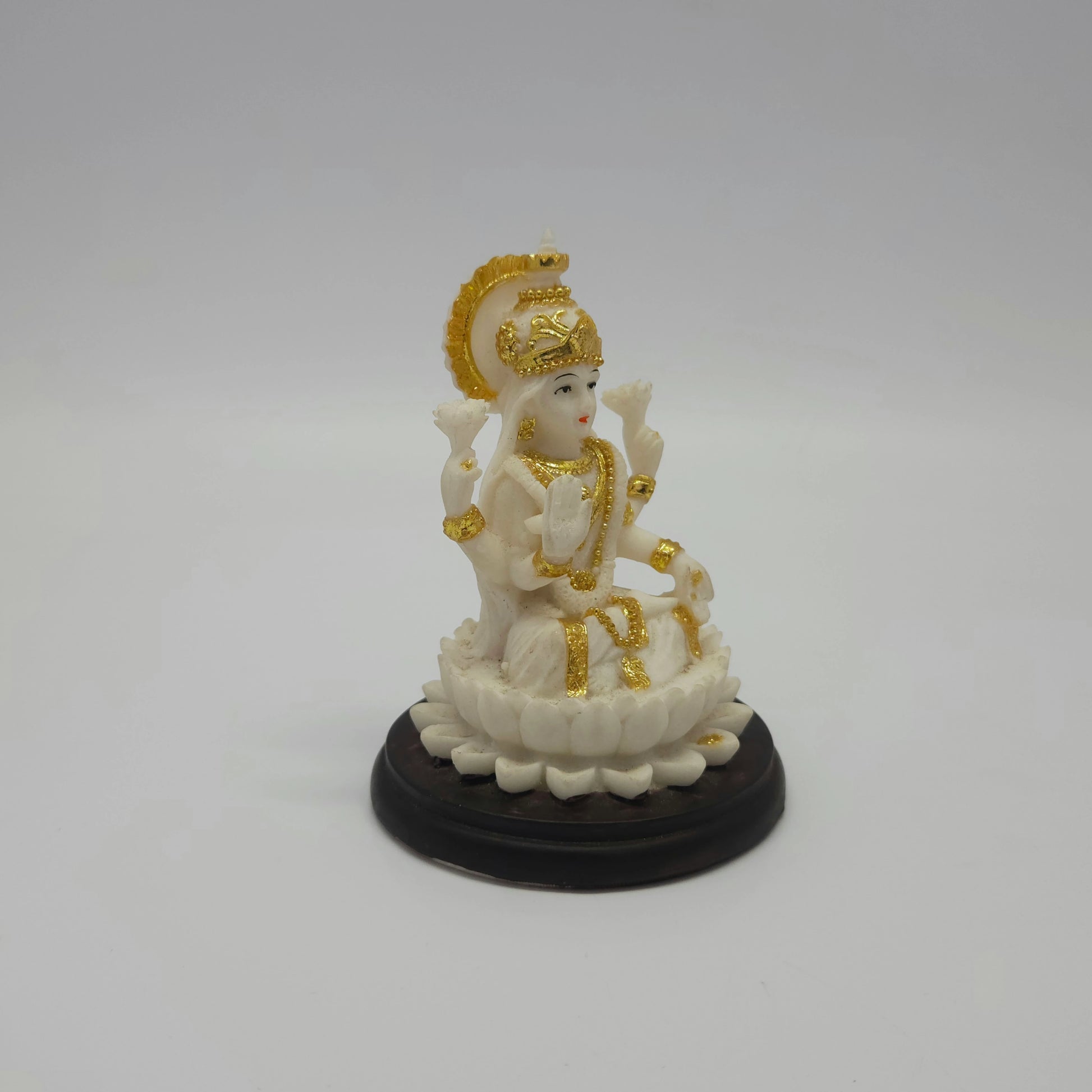 Angled front left perspective of the white resin Goddess Lakshmi figurine highlighting her traditional blessing posture and dark stepped base.