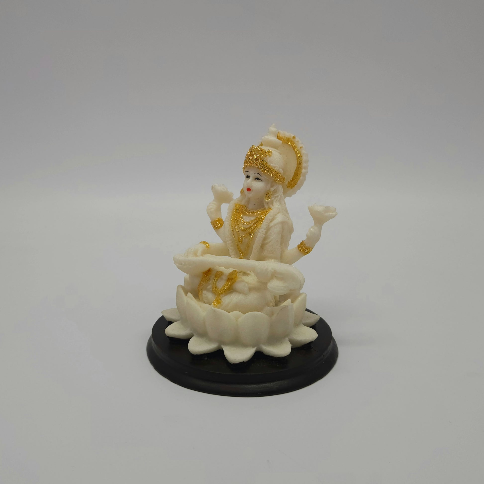 Angled front left perspective of the white resin Goddess Saraswati figurine highlighting her holding the traditional veena instrument across her lap.
