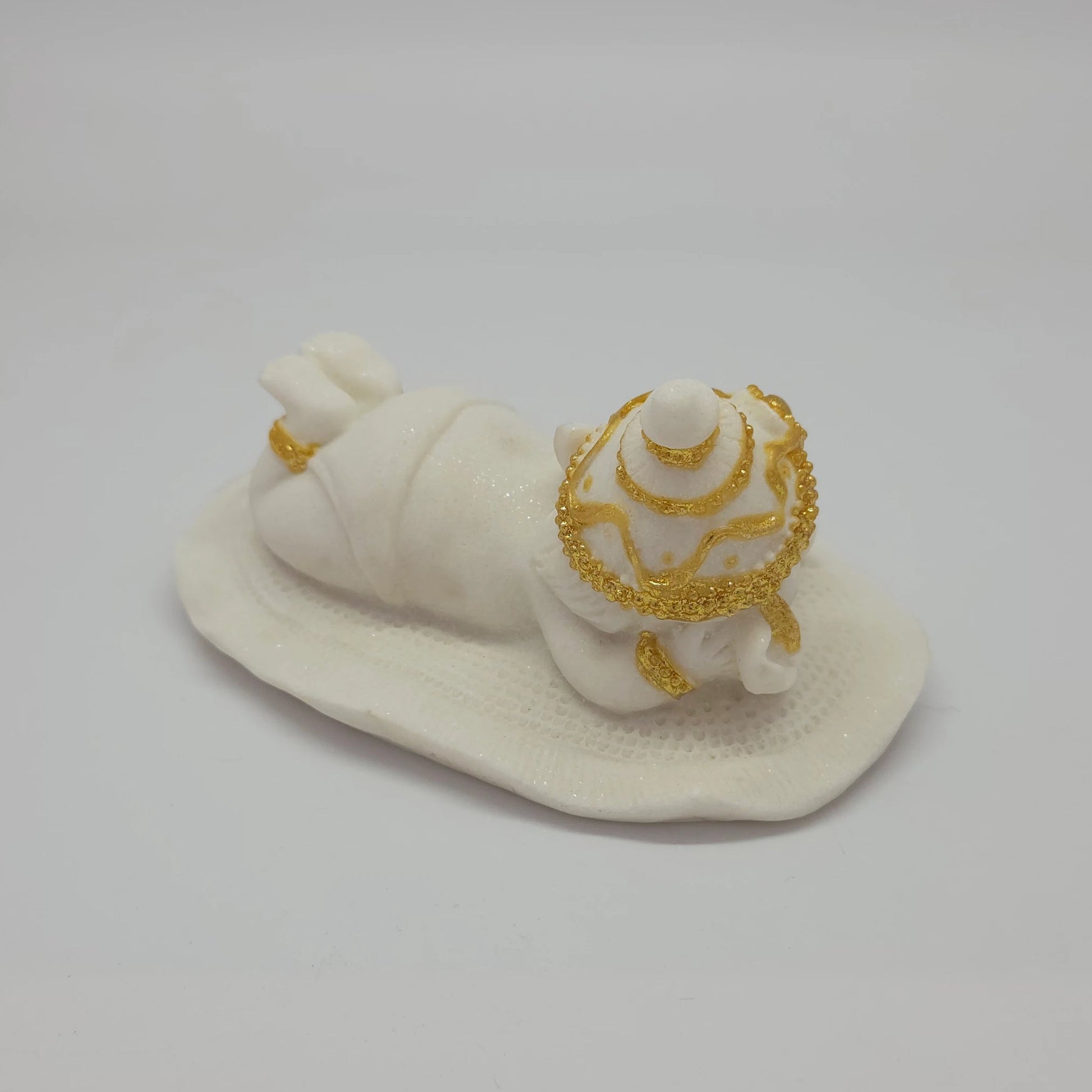 Side perspective of the white marble-finish resin Ganesha figurine highlighting the gold anklets and smooth body texture