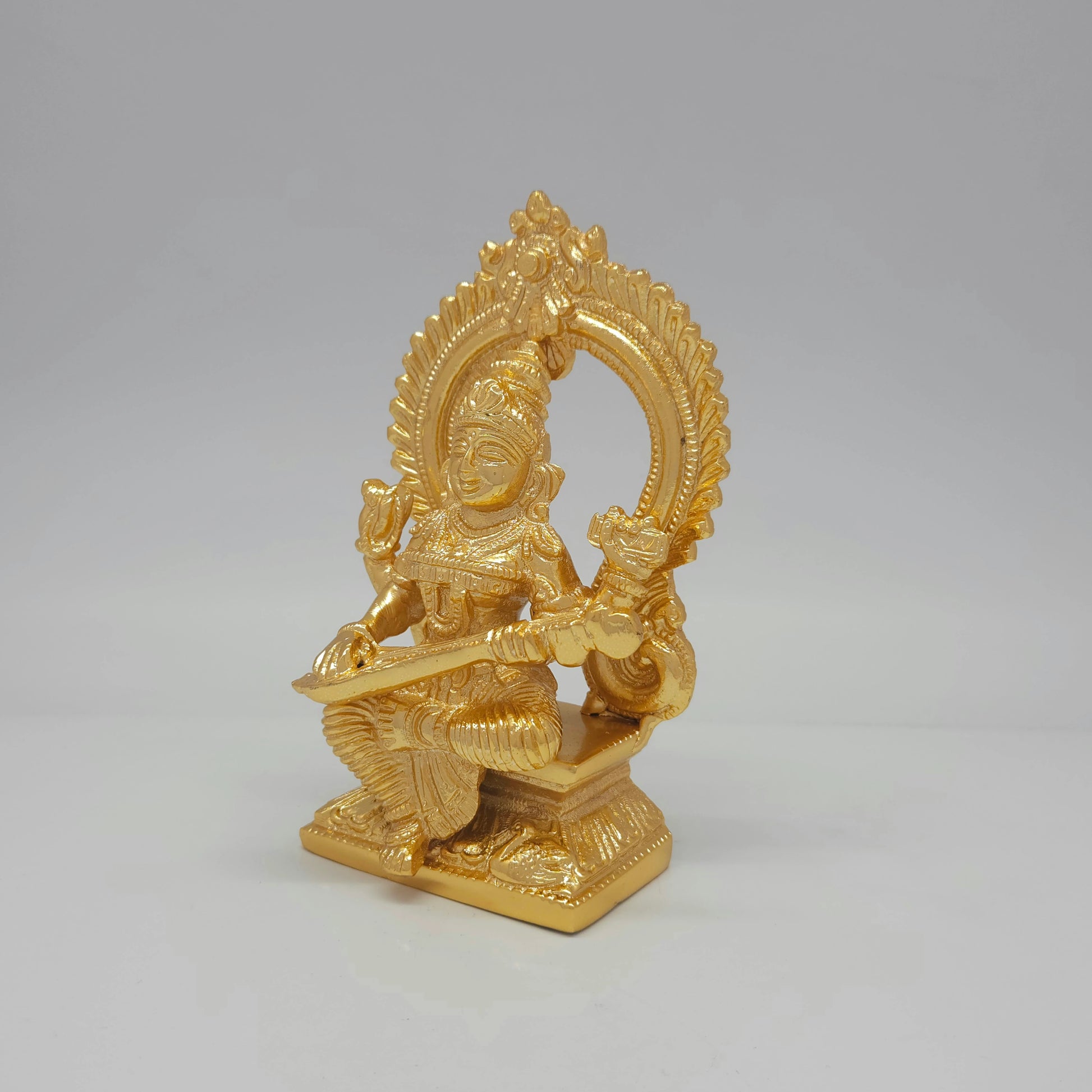 Left three-quarter angle view of the anti-tarnish gold powder-coated brass Saraswati idol showcasing the fine details of the throne base.