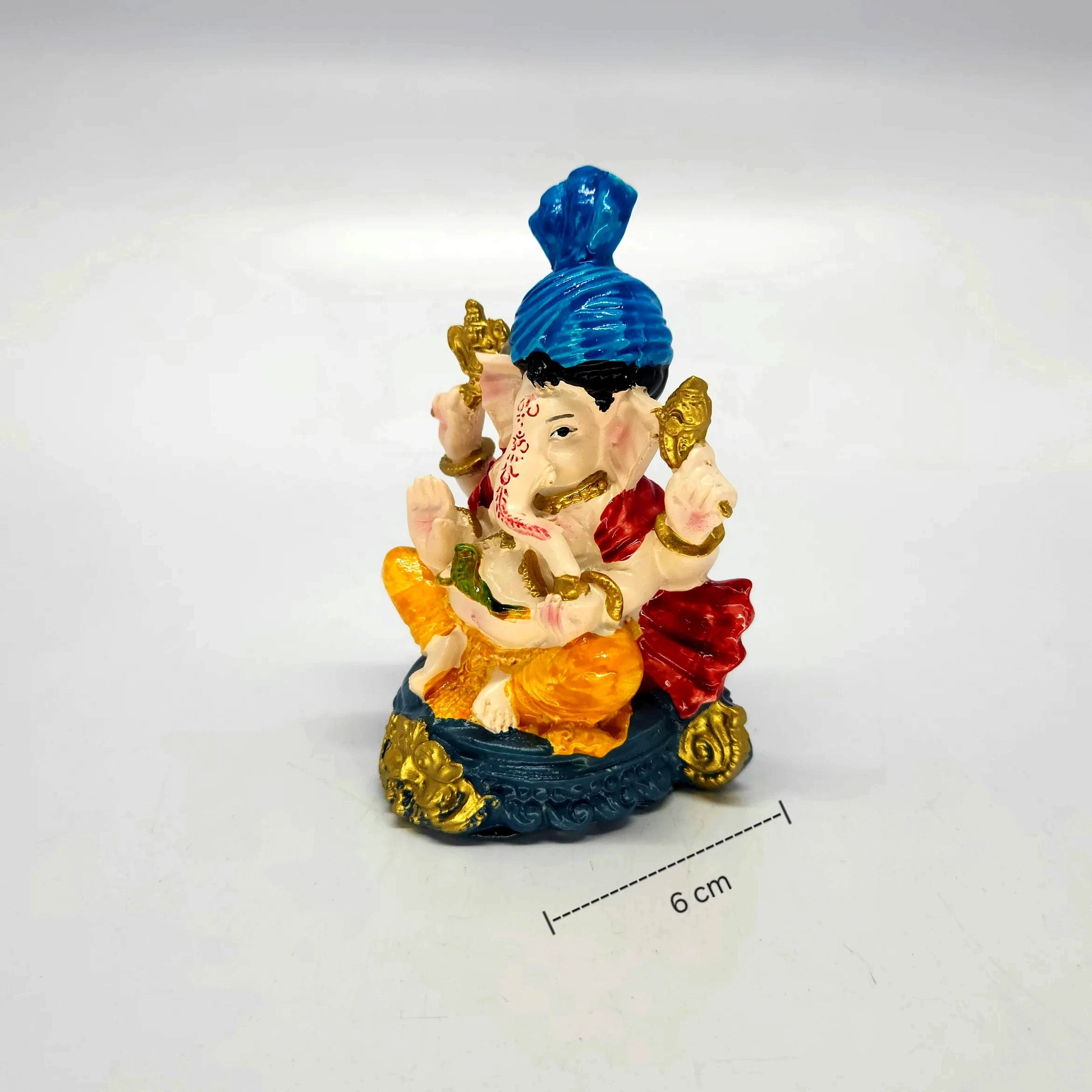 Close-up view of the independent 11cm white resin Ganesha idol wearing a bright blue turban and yellow dhoti.