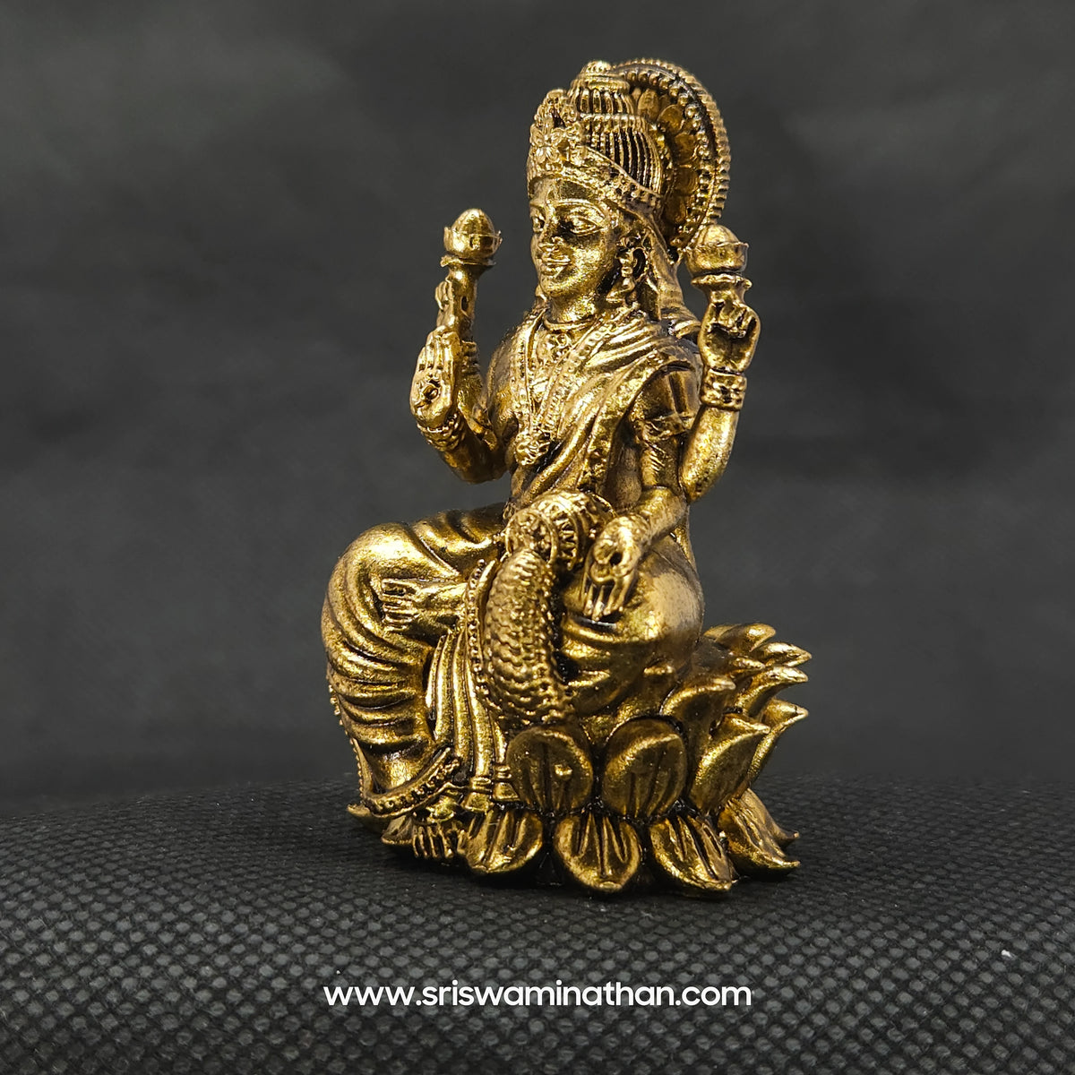 Three-quarter front right perspective view of the compact brass Aishwarya Lakshmi statue showcasing the detailed crown and the open palm with the distinct Om symbol.