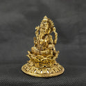Three-quarter front left perspective view of the two and a half inch brass Ganesha statue on a round lotus peedam highlighting the sharp chiseled lines of his traditional weapon attributes.