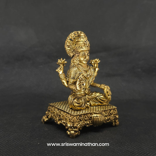 Three-quarter front right perspective view of the two and a half inch brass Lakshmi statue highlighting the gorgeous crown and the detailed gold coins showering from her palm.