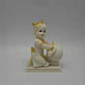 Straight front look of the white poly-marble Bal Krishna sculpture highlighting his golden crown ornaments and expressive eyes.