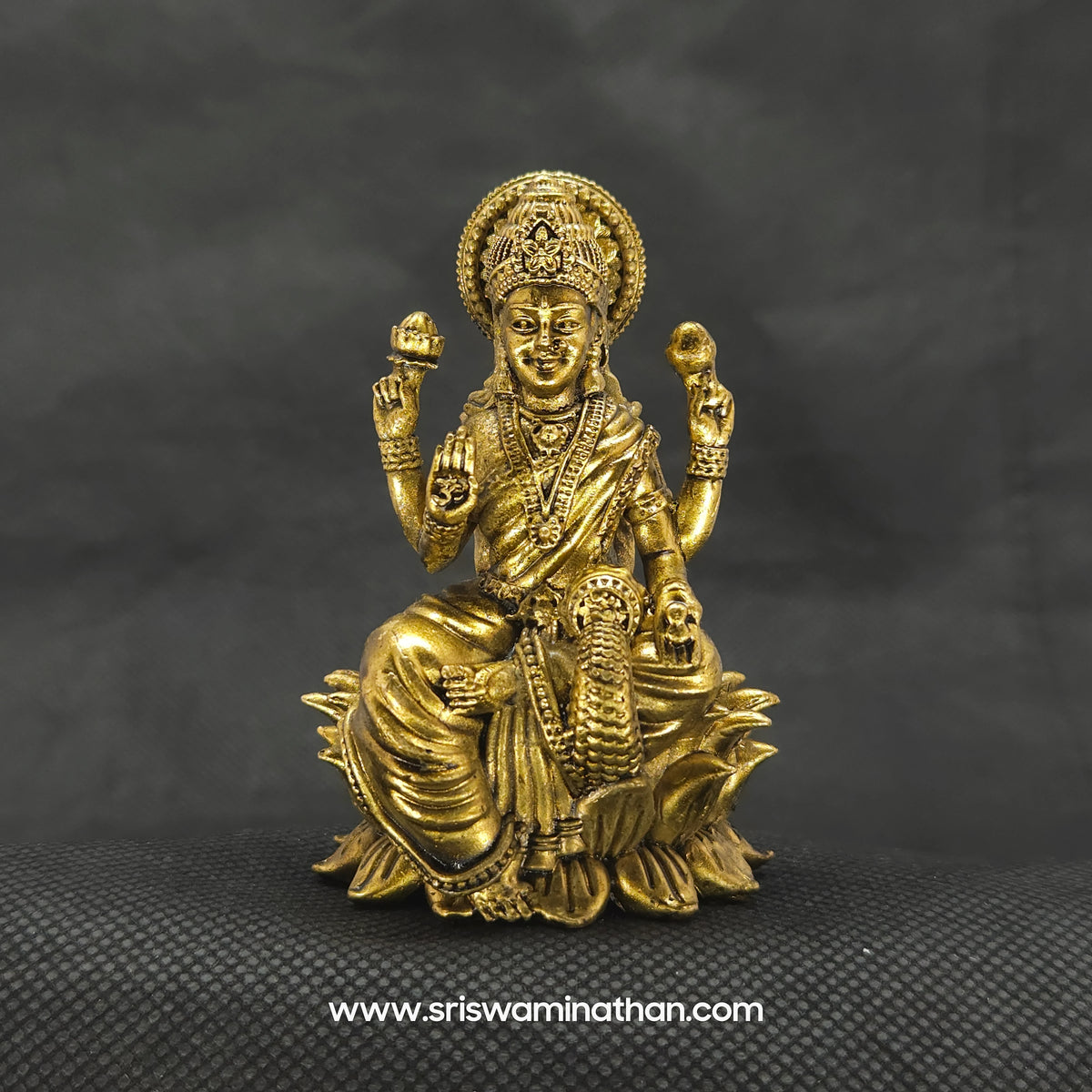 Straight front view of the premium solid brass Aishwarya Lakshmi statue showing the goddess seated on a bloomed lotus petal base pouring a stream of gold coins by Sri Swaminathan and Co.