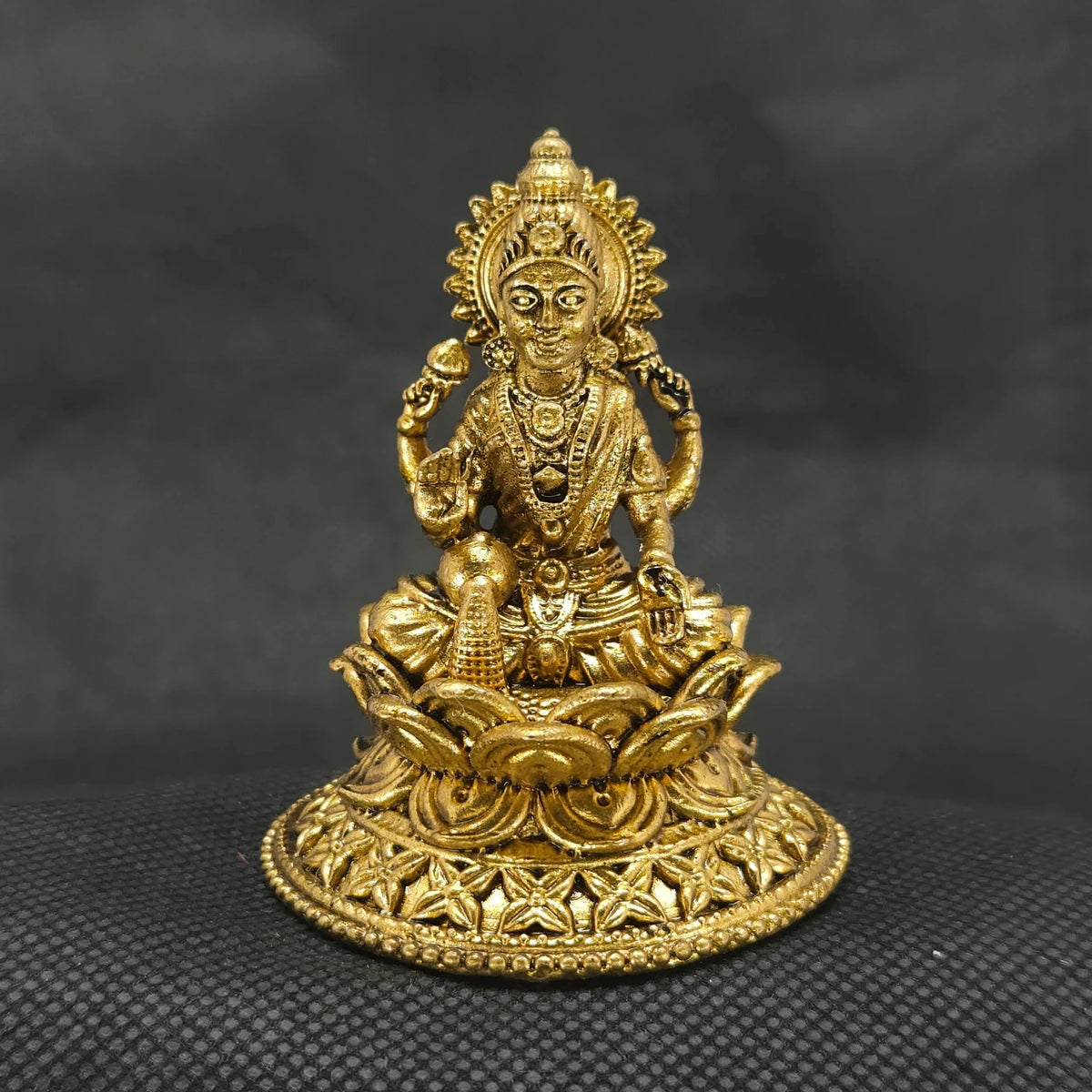 Straight front view of the premium solid brass Aishwarya Lakshmi statue showing the goddess seated on a circular lotus base pouring gold coins from a pot by Sri Swaminathan and Co.