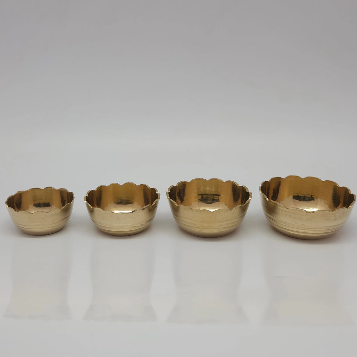 Direct straight front view of the premium solid brass bloom lotus katori bowl set showcasing the mini small big and large size variants arranged in a horizontal row by Sri Swaminathan and Co.