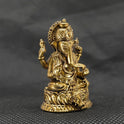 Three-quarter front left perspective view of the solid brass Ganesha statue highlighting the chiseled traditional weapon features and the deep thickness of the casting.
