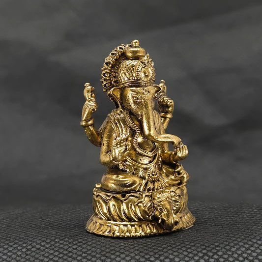 Three-quarter front left perspective view of the solid brass Ganesha statue highlighting the chiseled traditional weapon features and the deep thickness of the casting.
