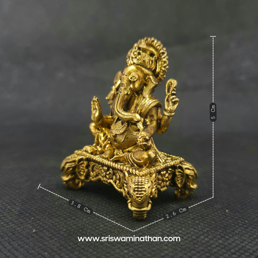 Three-quarter front right perspective view of the brass Ganesha statue showcasing his prominent fat abdomen, the detailed laddu sweet, and the ornate elephant heads on the base corners.