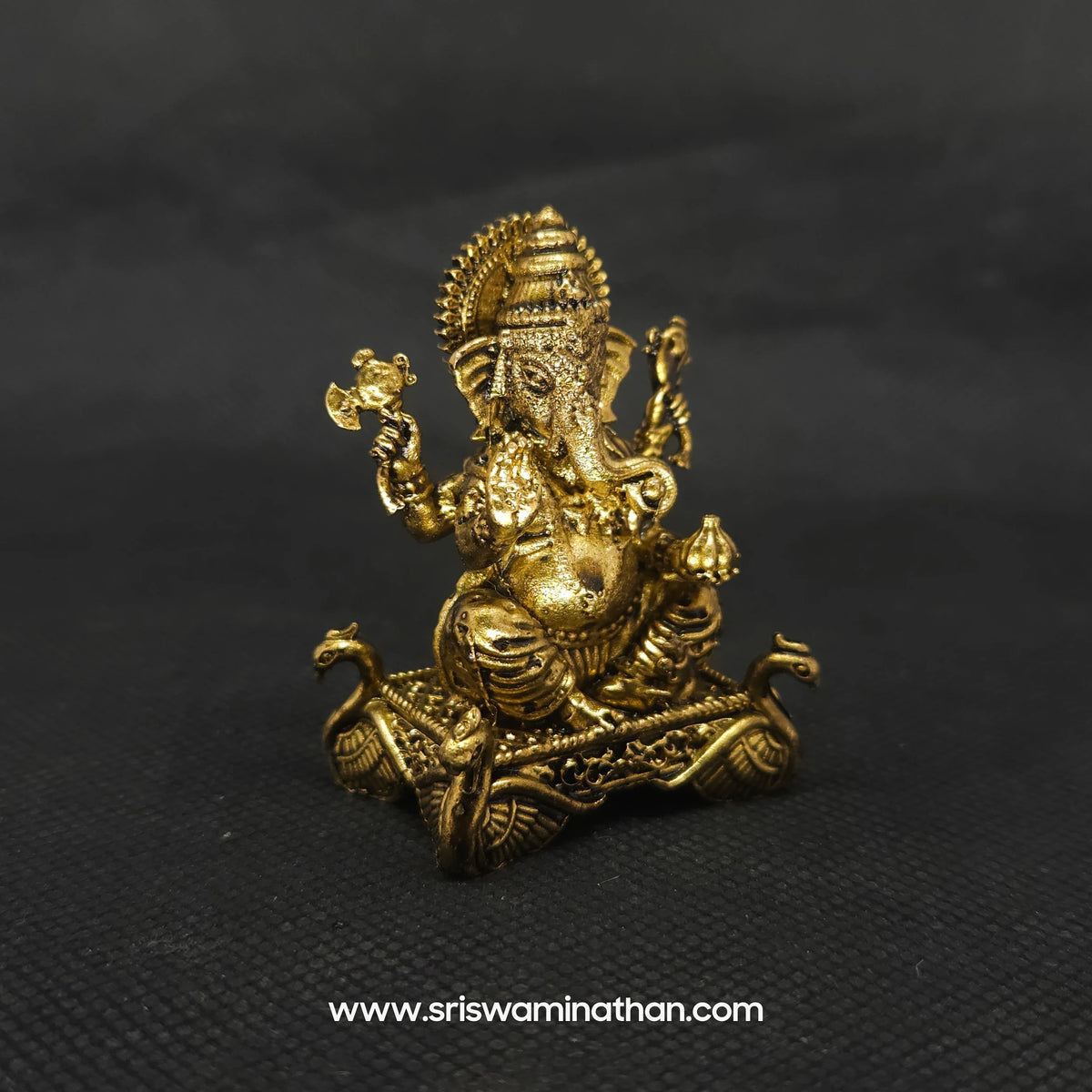 Three-quarter left side view of the solid brass Ganesha statue on a hamsa peedam showcasing the deep three-dimensional thickness of the casting and traditional weapon attributes.
