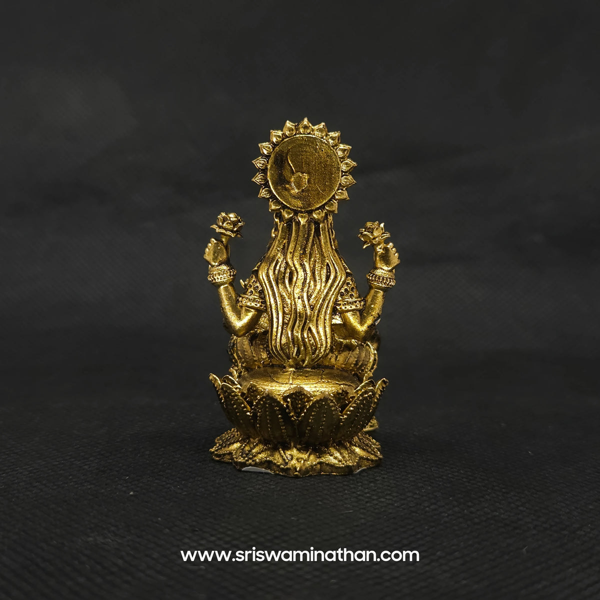 Direct straight back view of the solid brass Kubera Lakshmi statue demonstrating the detailed rear surface of the halo crown and lengthy hair curls over the base.