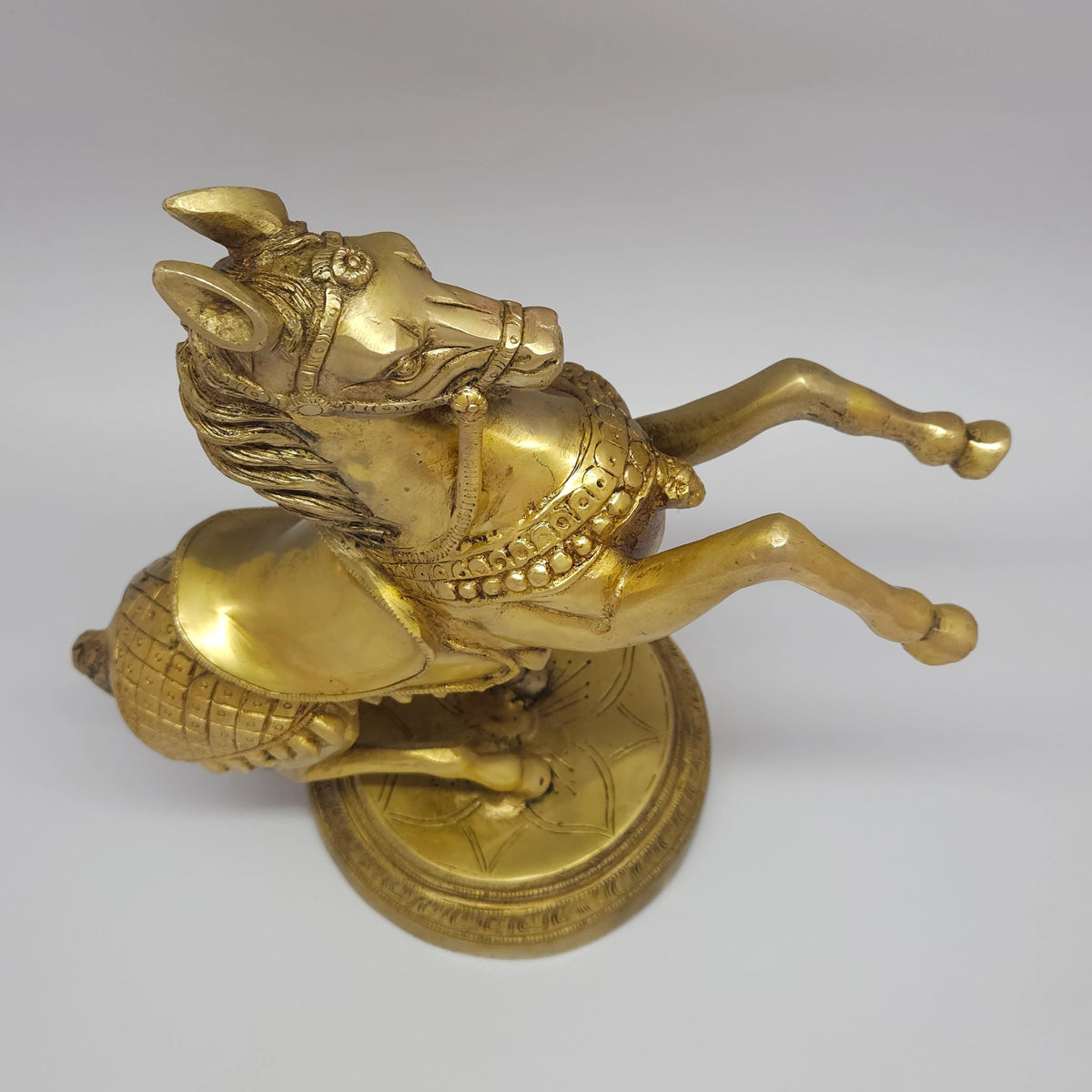 Tilted overhead top view looking down at the pure brass rearing horse statue to showcase the balance of the upper body and base diameter width.