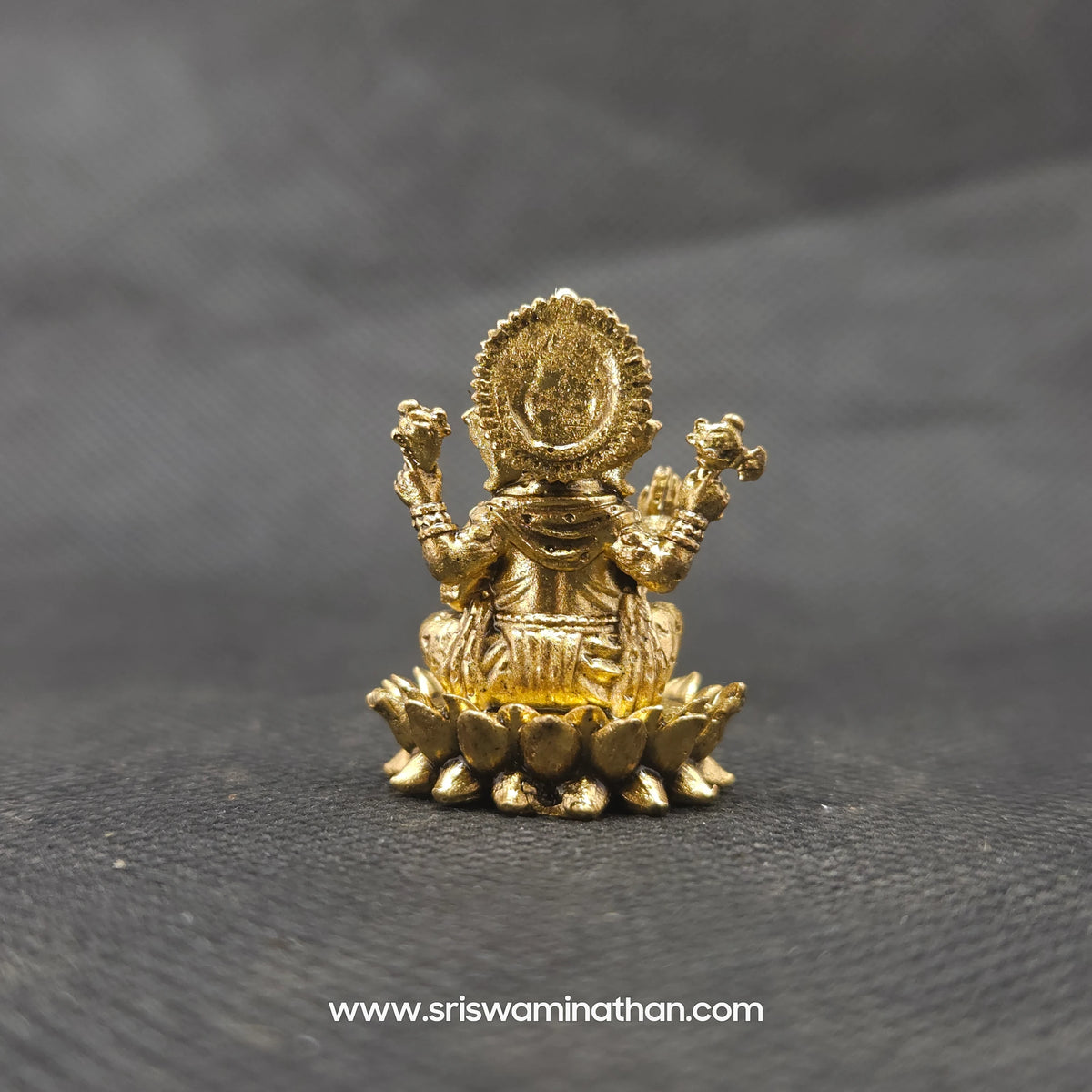 Direct straight back view of the one inch solid brass Ganesha statue demonstrating the detailed rear surface of the sunburst halo crown armor and back contours of the round lotus seat.