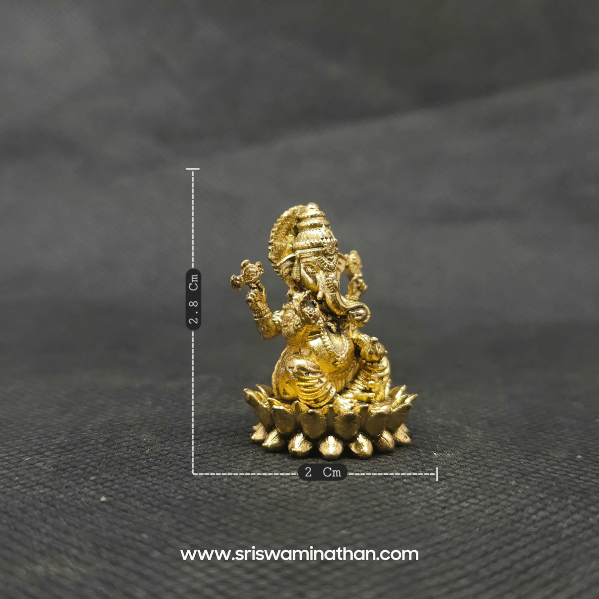 Three-quarter front left perspective view of the one inch brass Ganesha statue highlighting the chiseled lines of his traditional weapon armors and the deep three-dimensional thickness of the casting.