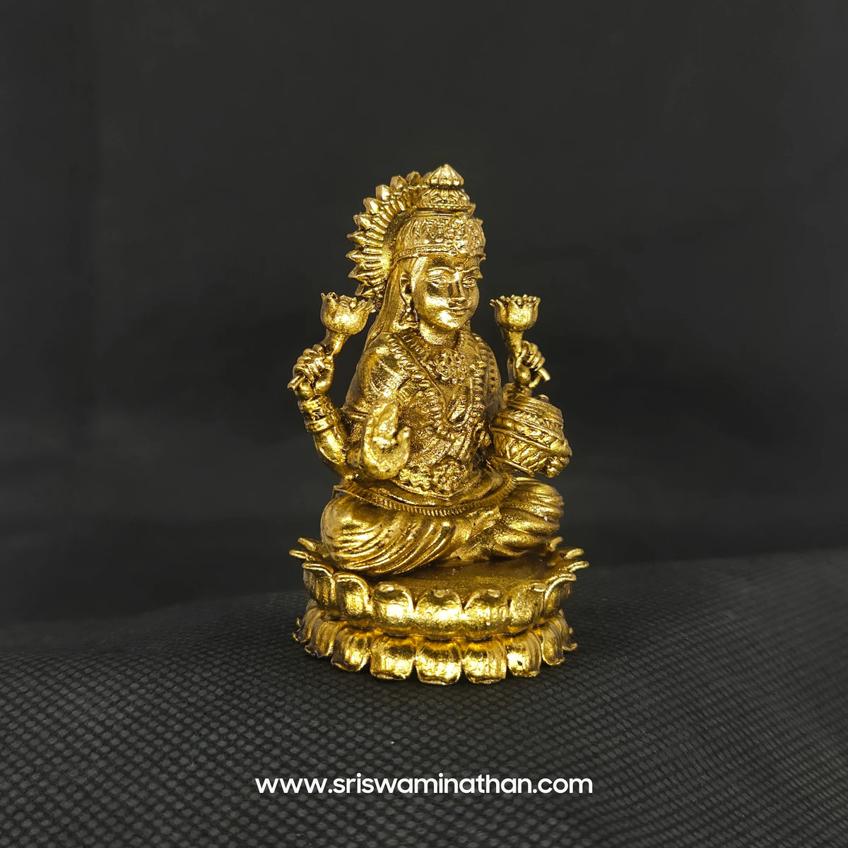 Three-quarter front left perspective view of the solid brass seated Lakshmi statue with Akshaya Patram highlighting her lengthy hair curls and the deep three-dimensional thickness of the casting