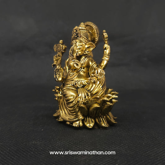 Three-quarter front left perspective view of the solid brass seated Lalita Ganapati statue highlighting the sharp detailed lines of the attributes and the deep three-dimensional thickness of the casting.

