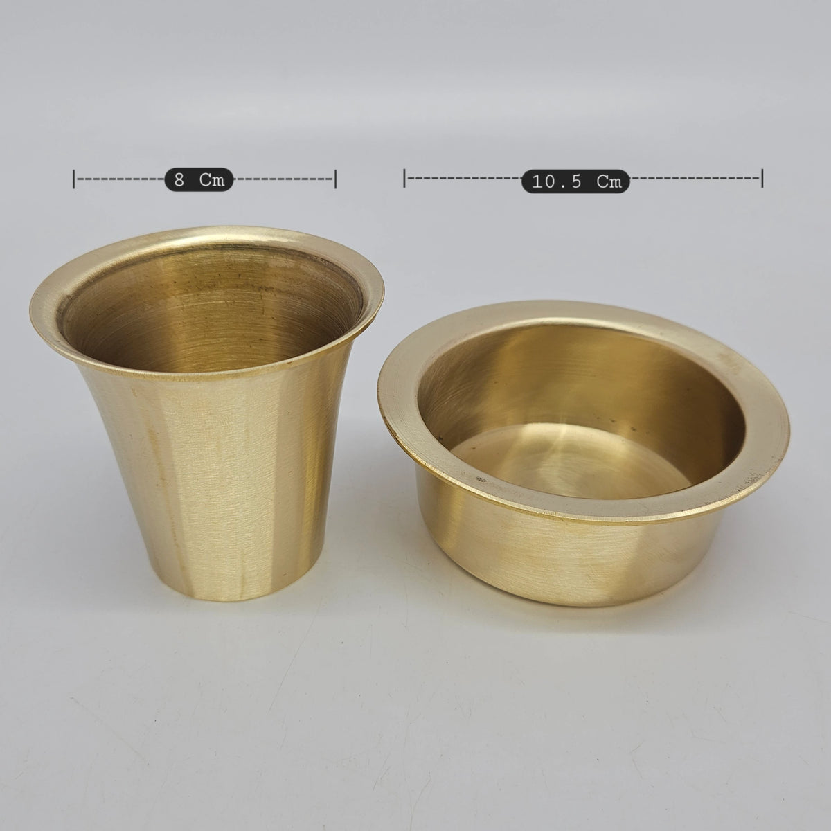 Top down angle view looking directly into the open brass gold finished bronze tumbler and dawara to highlight the polished inner liquid chambers