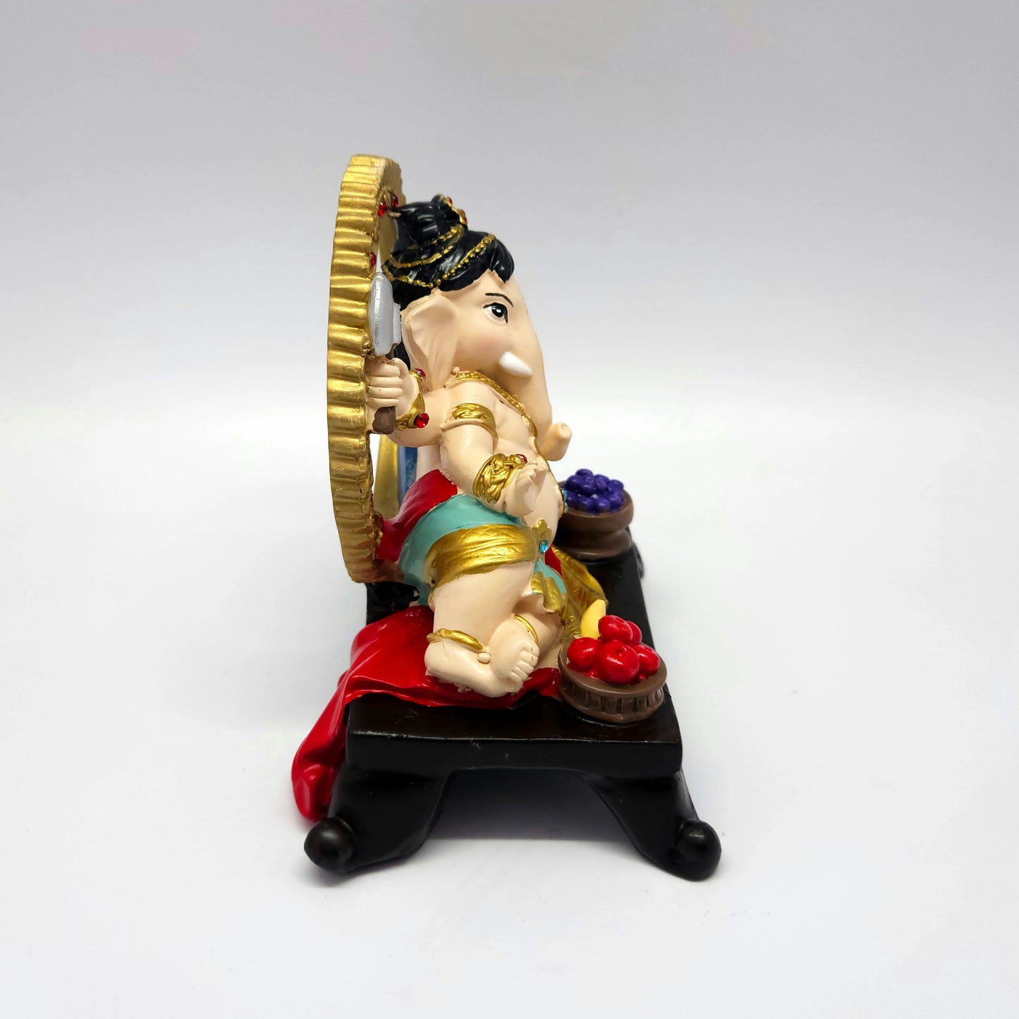 Left profile image of the resting Vinayagar idol showcasing how the red cloth drapes gracefully over the edge of the dark base