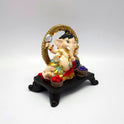 Three-quarter perspective of a multi-color resin Ganpati statue highlighting the gold halo and blue rhinestone placements.