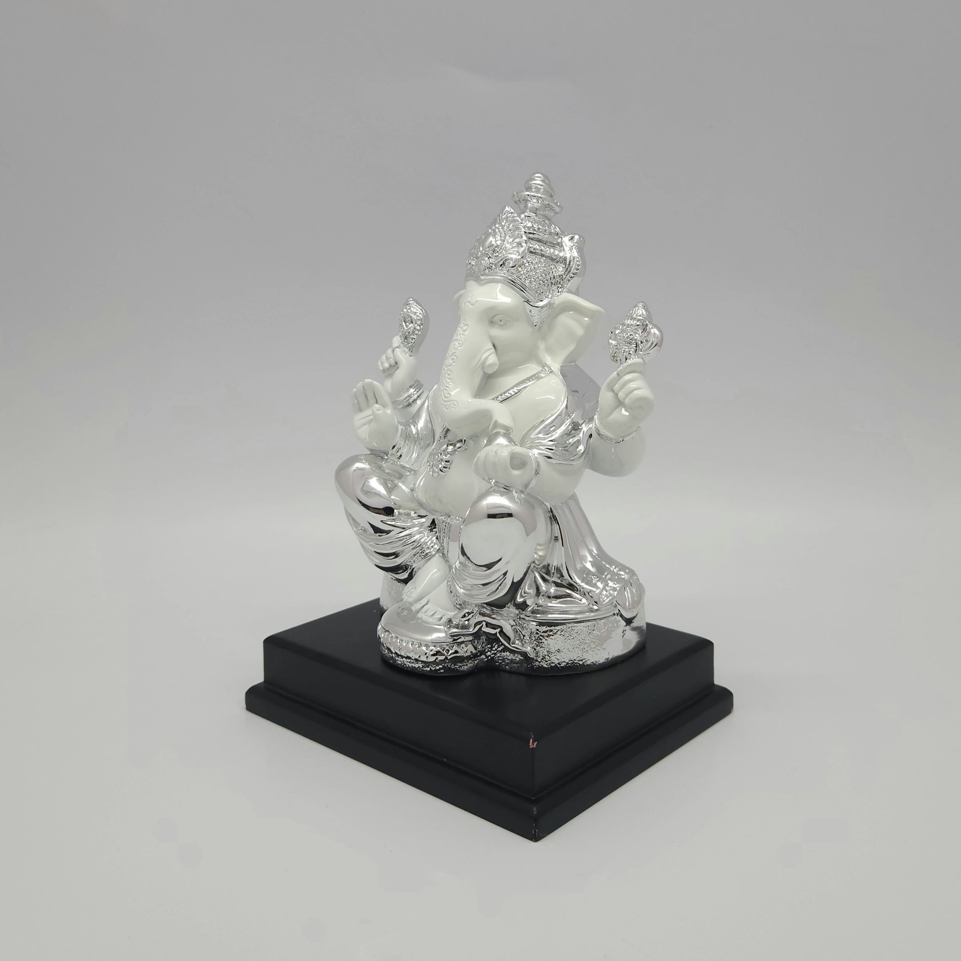 Left three-quarter angle view of the silver electroplated resin Ganpati idol showcasing the thick square dark pedestal stand.