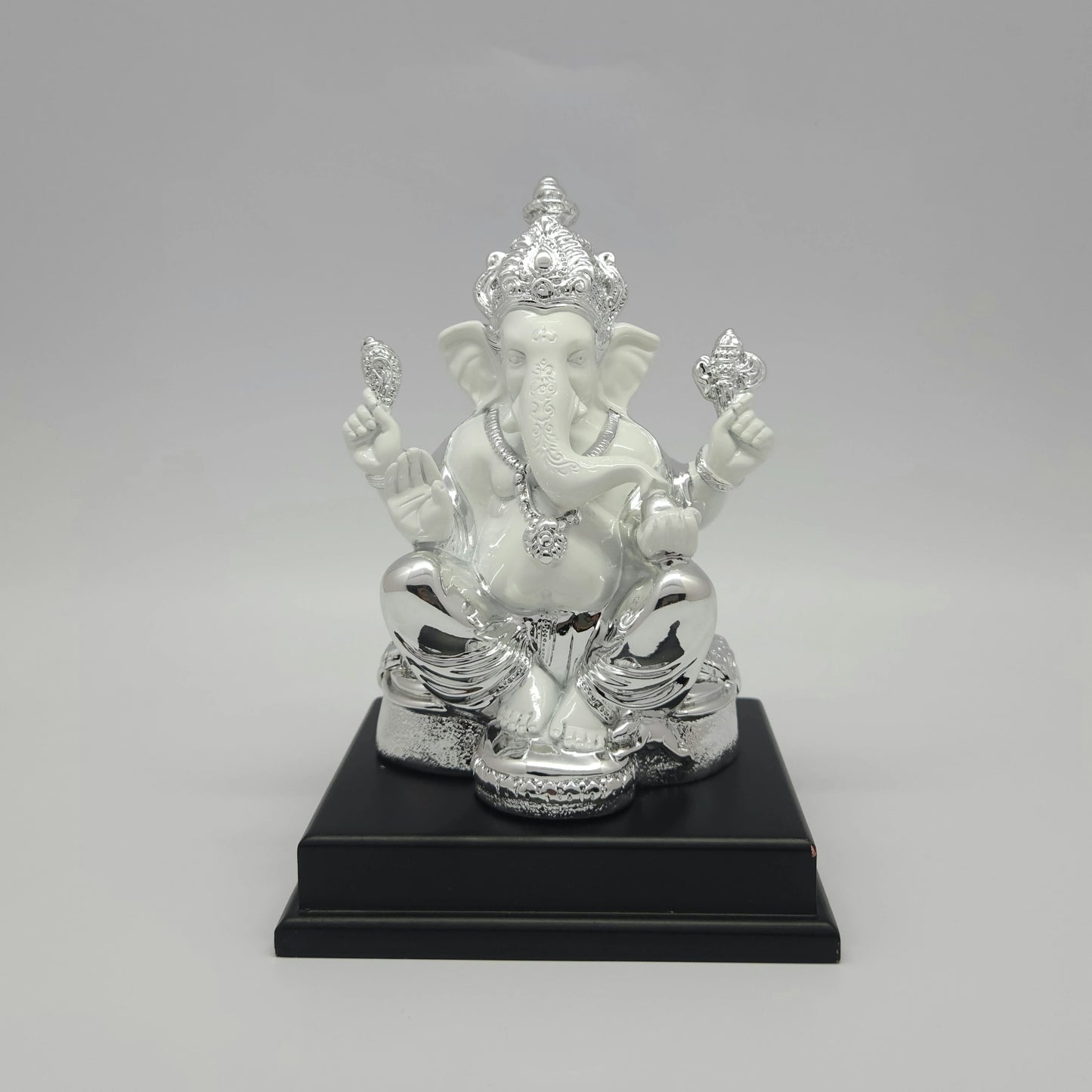Front view of a 19cm silver plated and white marble finish resin Ganesha statue mounted on a black stepped pedestal by Sri Swaminathan and Co.