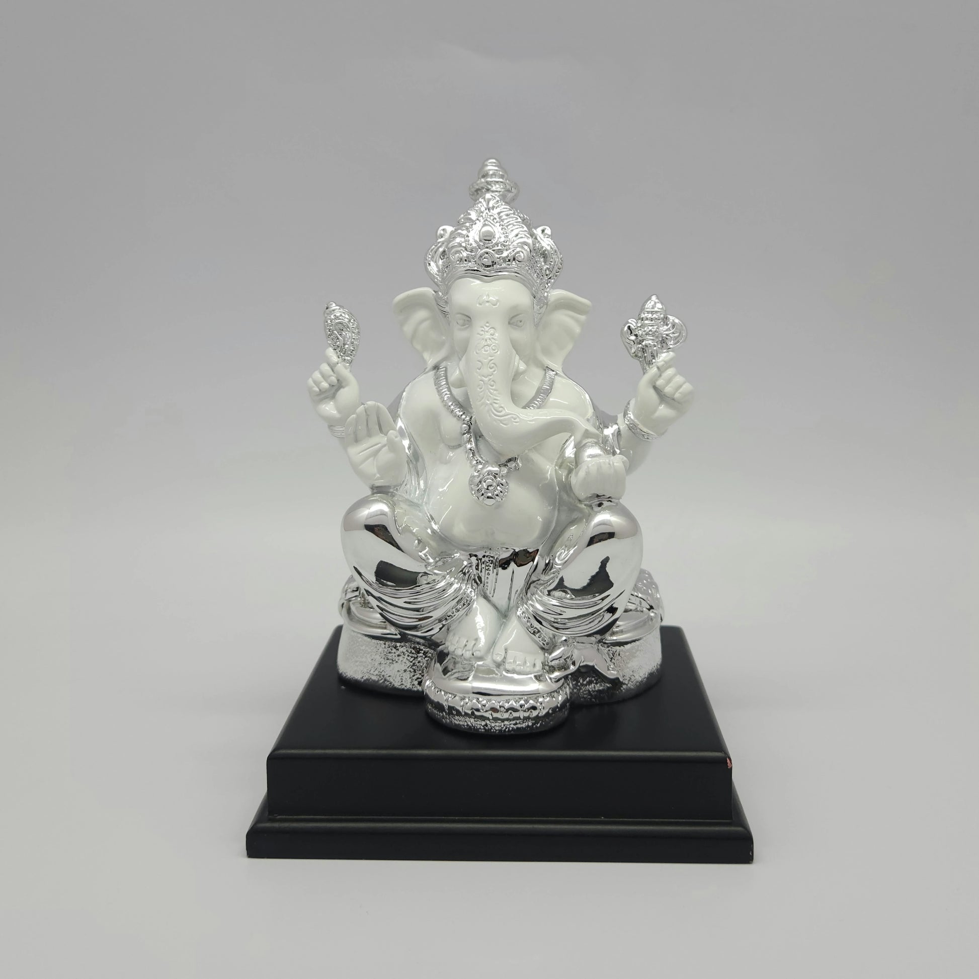 Front view of a 19cm silver plated and white marble finish resin Ganesha statue mounted on a black stepped pedestal by Sri Swaminathan and Co.