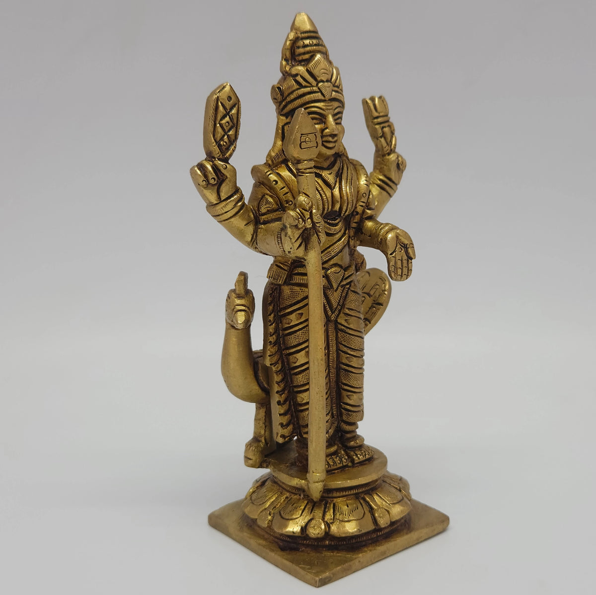 Three-quarter front right perspective view of the six point one inch brass Kumara statue showcasing the extended lines of the outcurved peacock tail feathers.
