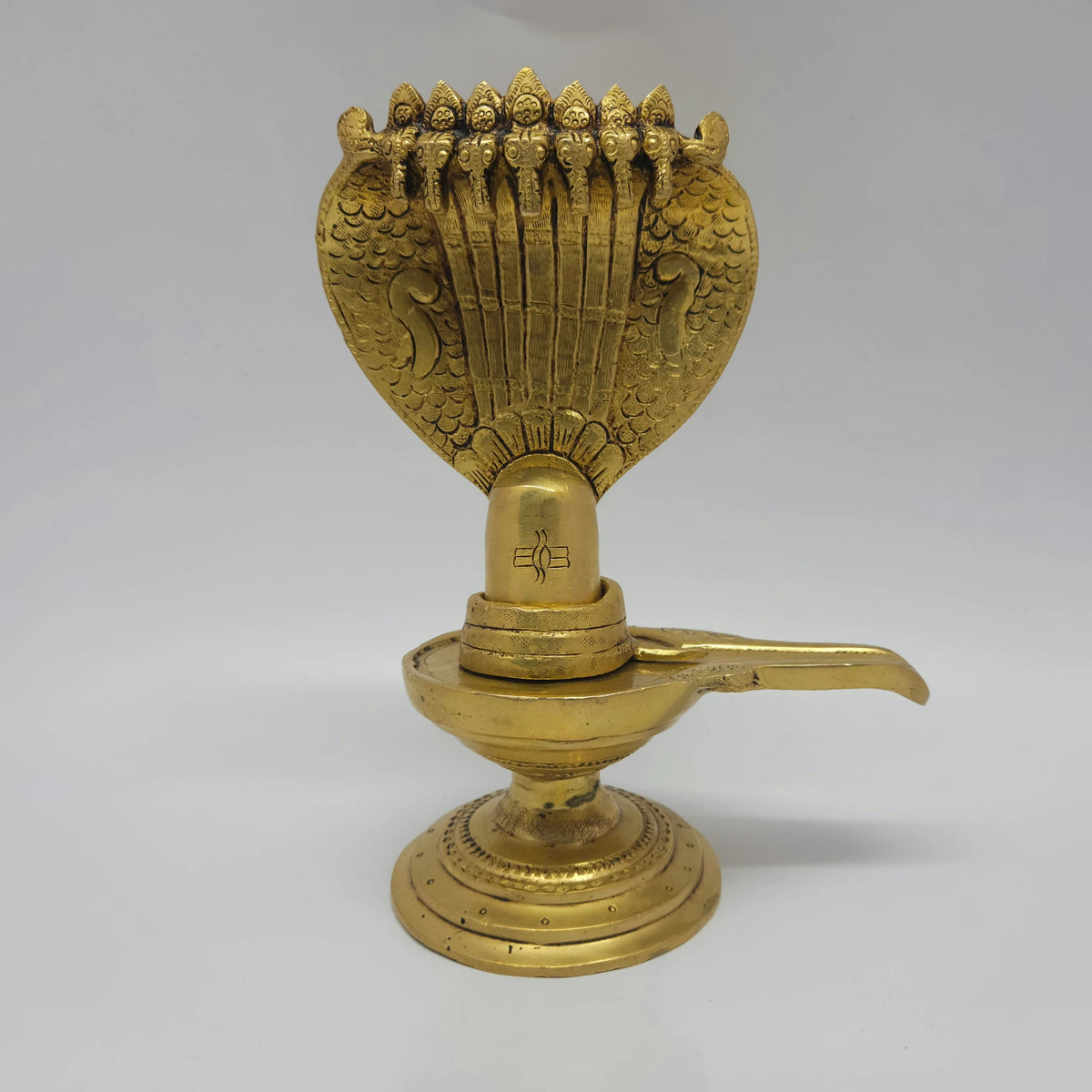 Straight front view of the 20cm solid cast brass antique look Shiva Lingam showing the detailed snake hood and the etched traditional tilak mark.