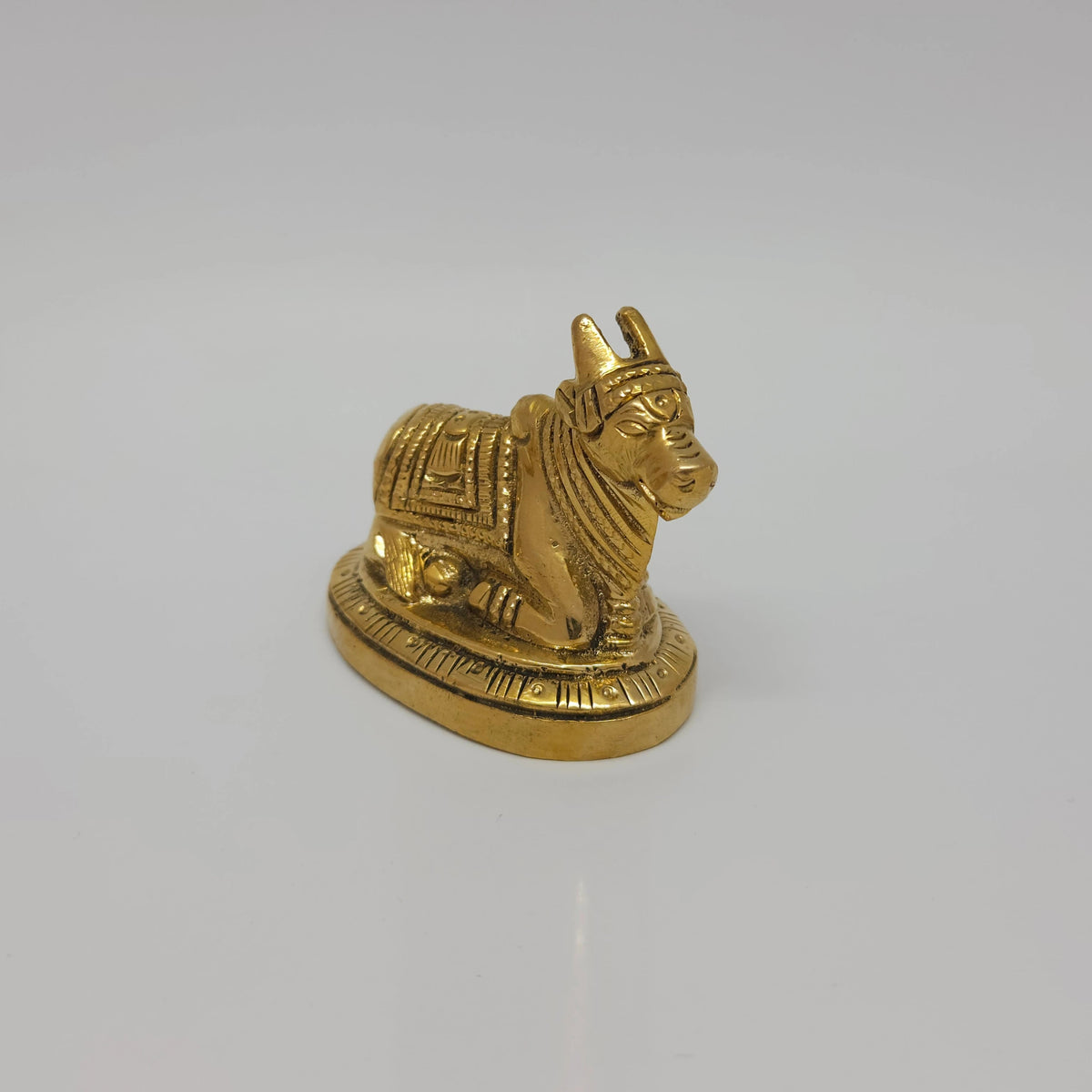 Close-up solo perspective view of the 2 inch handcrafted solid brass seated Nandi bull highlighting the hand-engraved hump and blanket details.