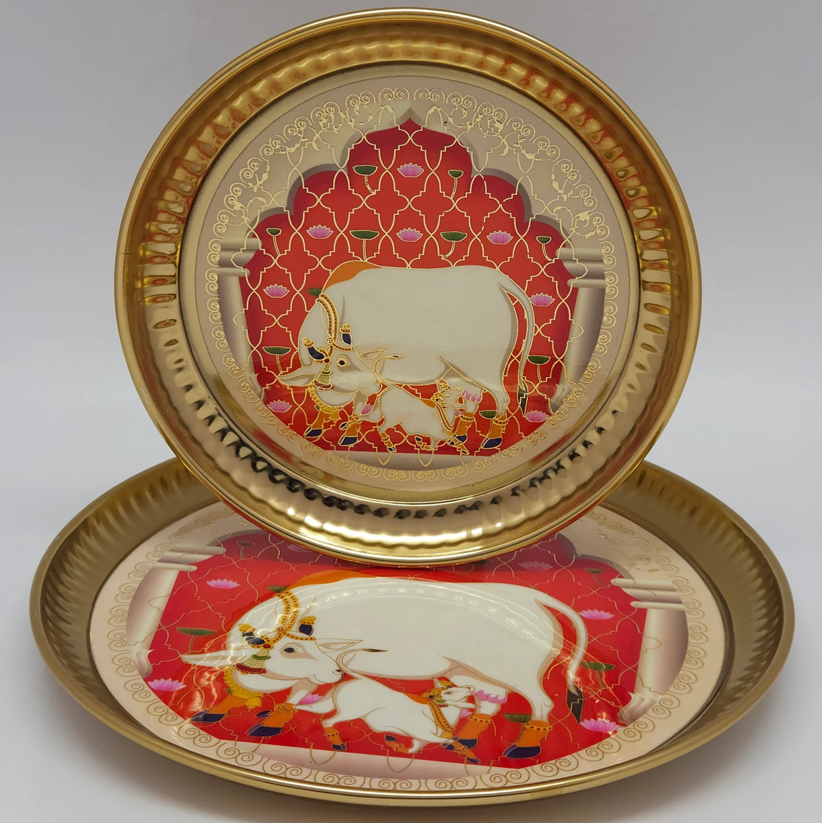 Display arrangement featuring two twelve inch brass coated pichwai plates with one positioned vertically behind the other to demonstrate the large caliber visual scales