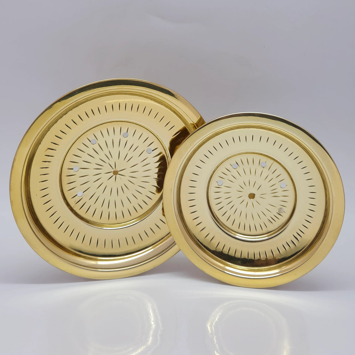 Alternative overhead profile view of the twenty two point five centimeter large brass kanji vadicattu plate highlighting natural bright white light glints reflecting off the hand polished surface.
