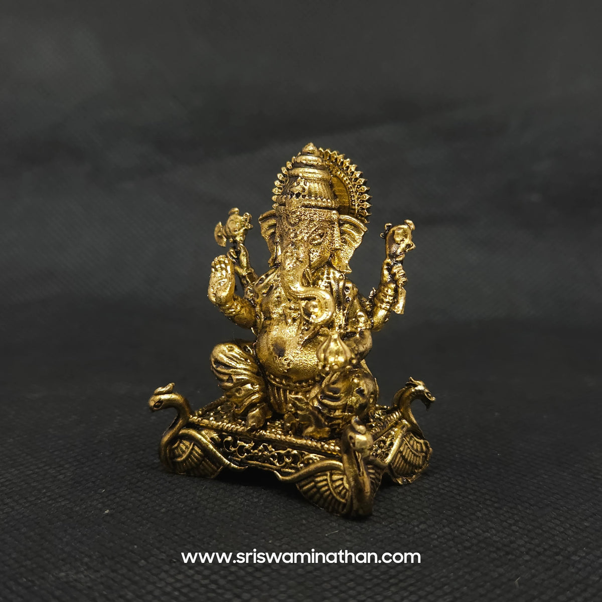 Three-quarter right side view of the two inch brass Ganesha statue with a prominent fat abdomen demonstrating the detailed curves of the right side profile and throne artwork.