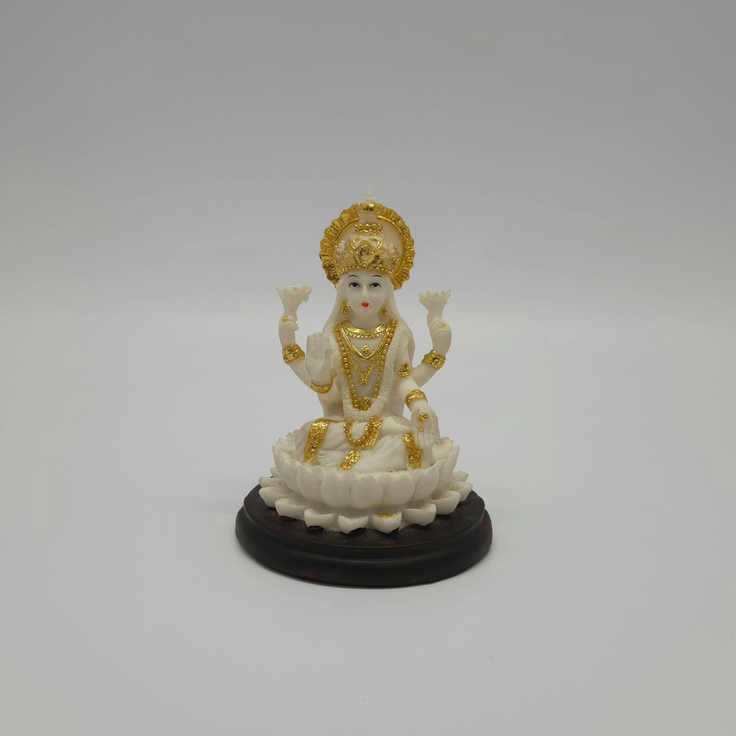 Front view of an 11cm white marble-finish resin Goddess Lakshmi statue seated on a lotus with a circular dark pedestal base by Sri Swaminathan and Co.