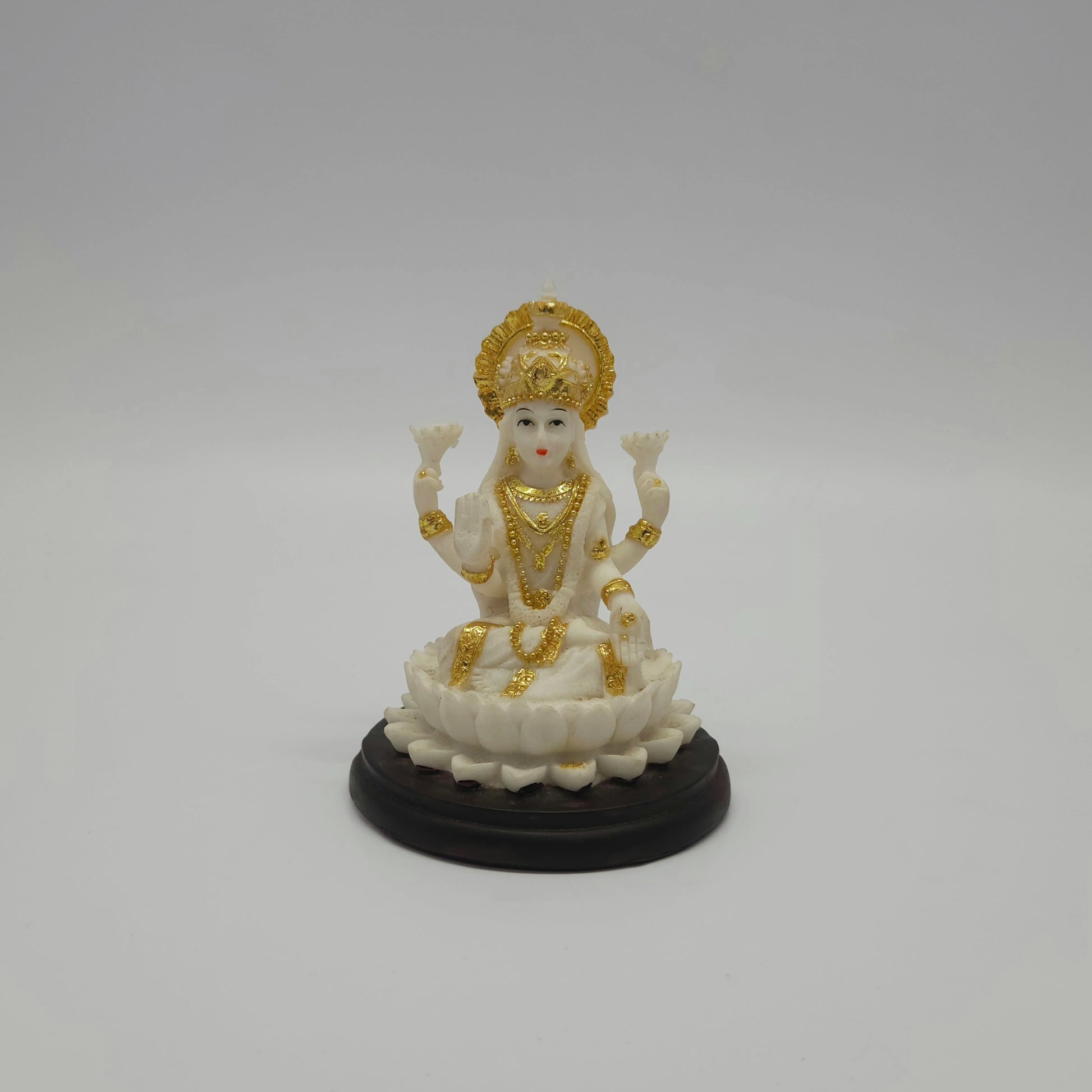 Front view of an 11cm white marble-finish resin Goddess Lakshmi statue seated on a lotus with a circular dark pedestal base by Sri Swaminathan and Co.