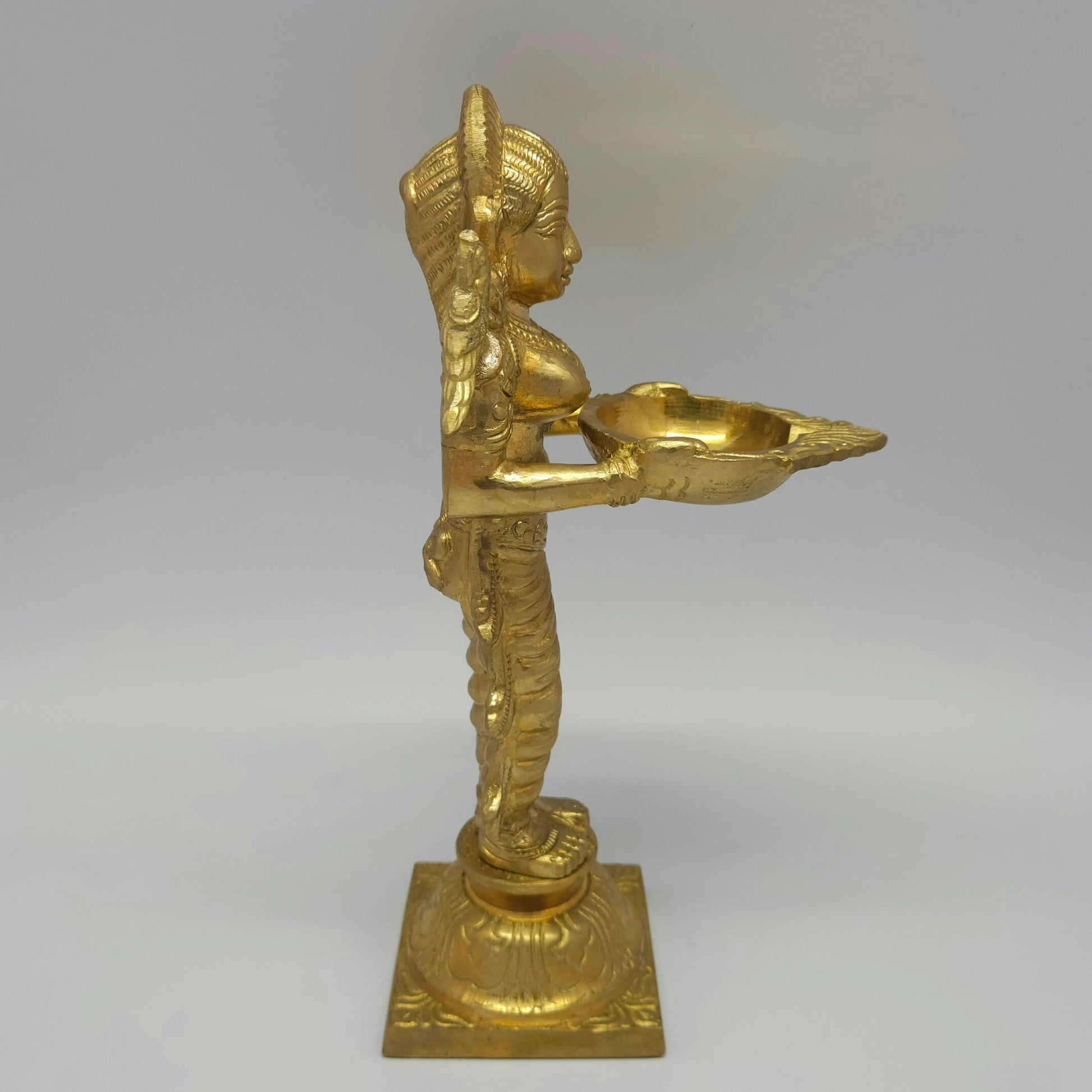 Sri Swaminathan and Co brass Deepalakshmi Pavai Vilakku lamp side posture view facing right side highlighting pleated dress folds and casting thickness