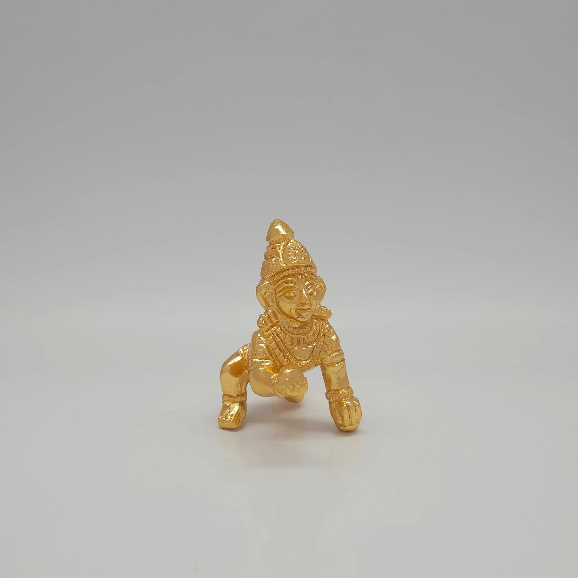 Sri Swaminathan and Co brass crawling Baby Krishna Santhana Krishna figurine gold finish 100g weight close up straight view of face highlighting the eyes smile and forehead markings