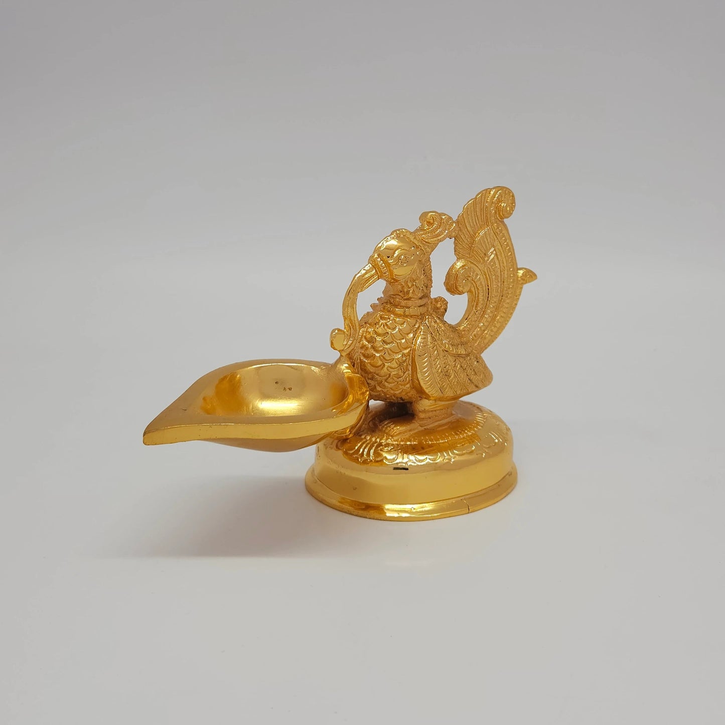 Sri Swaminathan and Co brass decorative peacock showpiece gold finish 610g 45 degree left pose corner view highlighting chiseled wing textures and crown profile
