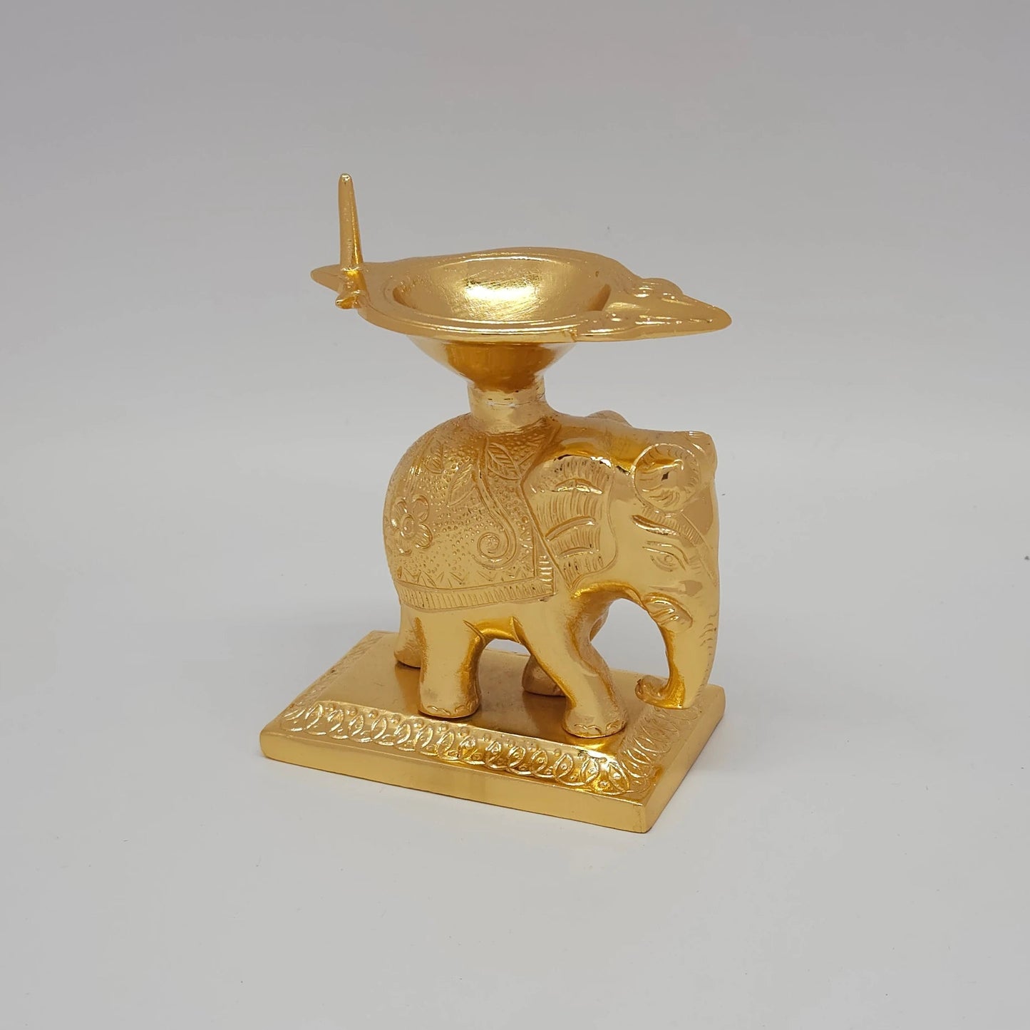 Sri Swaminathan and Co brass elephant diya stand gold powder coated 6 inch 14cm height 45 degree right pose corner view focusing on trunk profile and rectangular pedestal base
