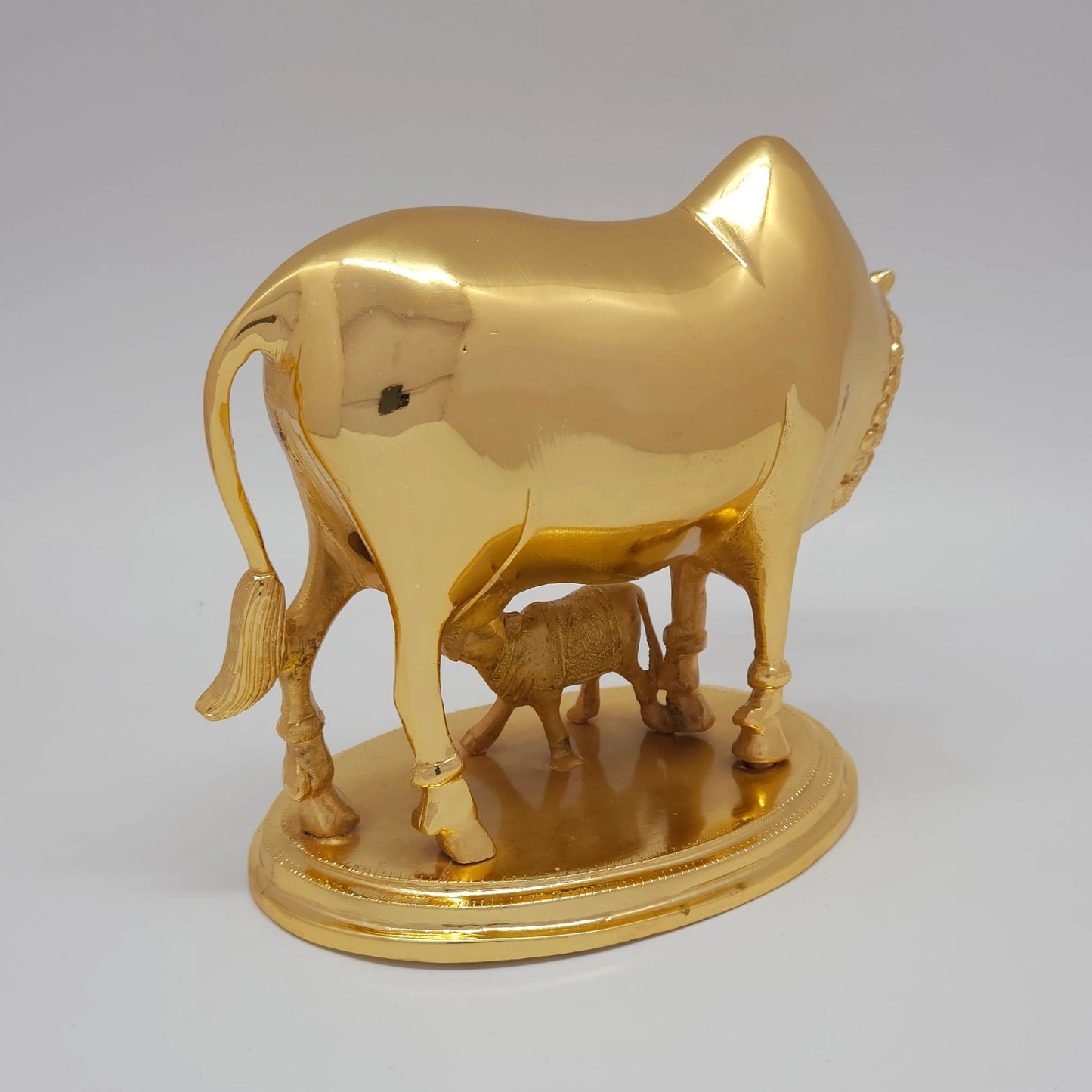 Sri Swaminathan and Co pure brass heavy Kamadhenu cow statue 2.25kg 45 degree right pose corner view focusing on calf drinking milk and base platform depth