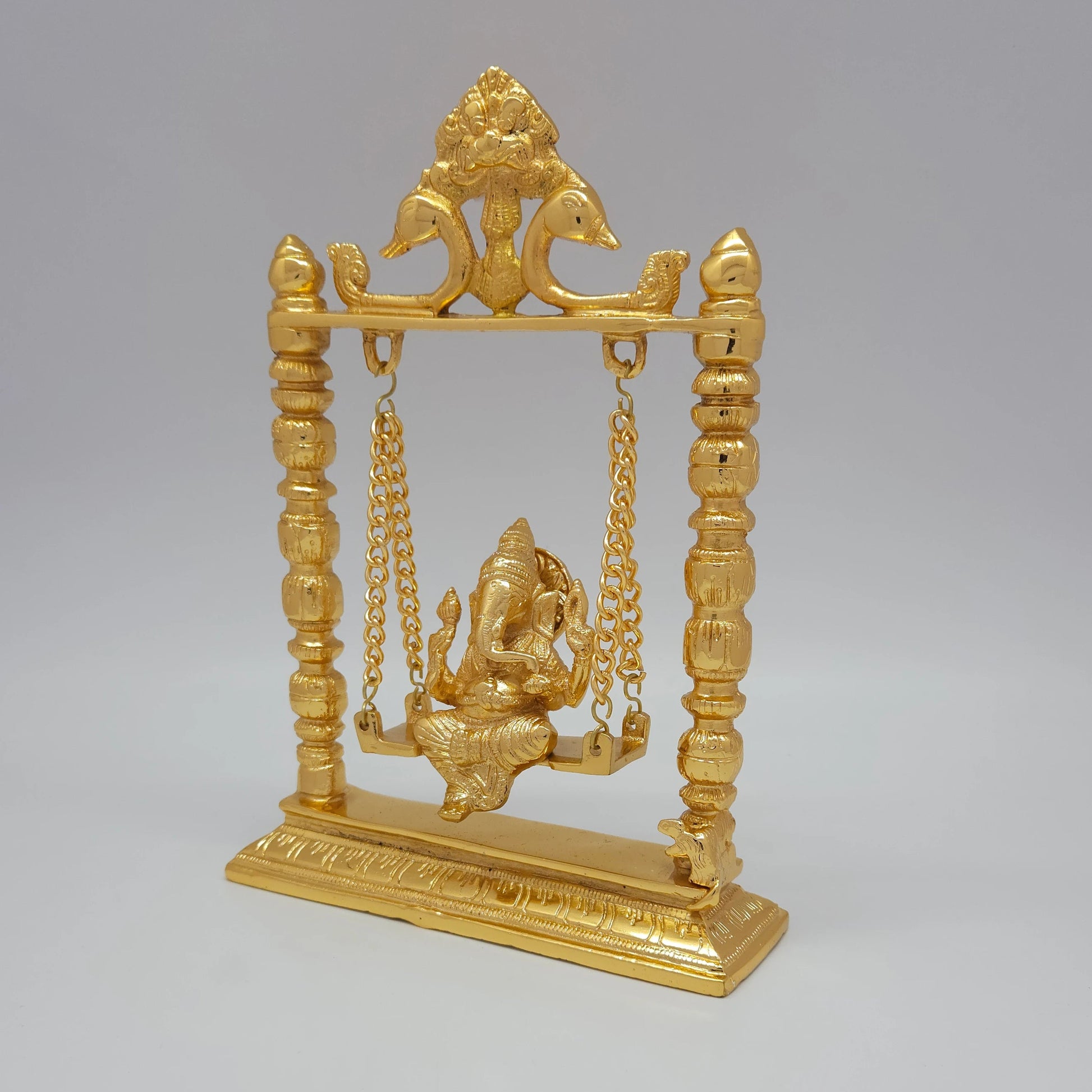 Sri Swaminathan and Co brass Jhula Ganesha swing statue gold finish 25cm height 45 degree left pose corner view highlighting linked chains and patterned column lines