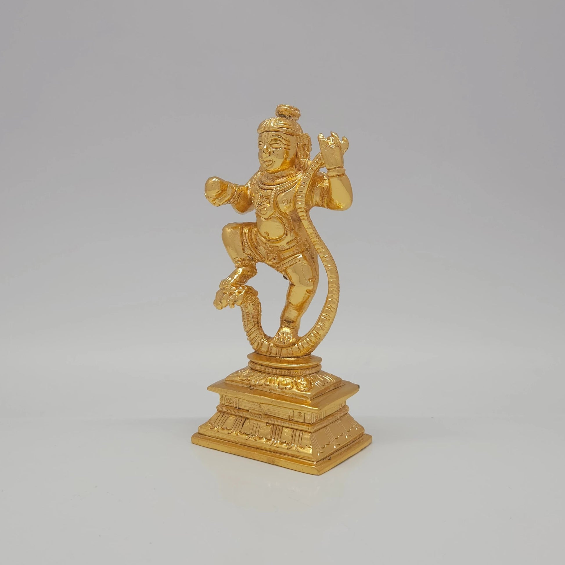Sri Swaminathan and Co brass Kaliya Nartana Krishna statue gold finish 300g weight 45 degree left pose corner view highlighting the chiseled serpent body loops and base profile