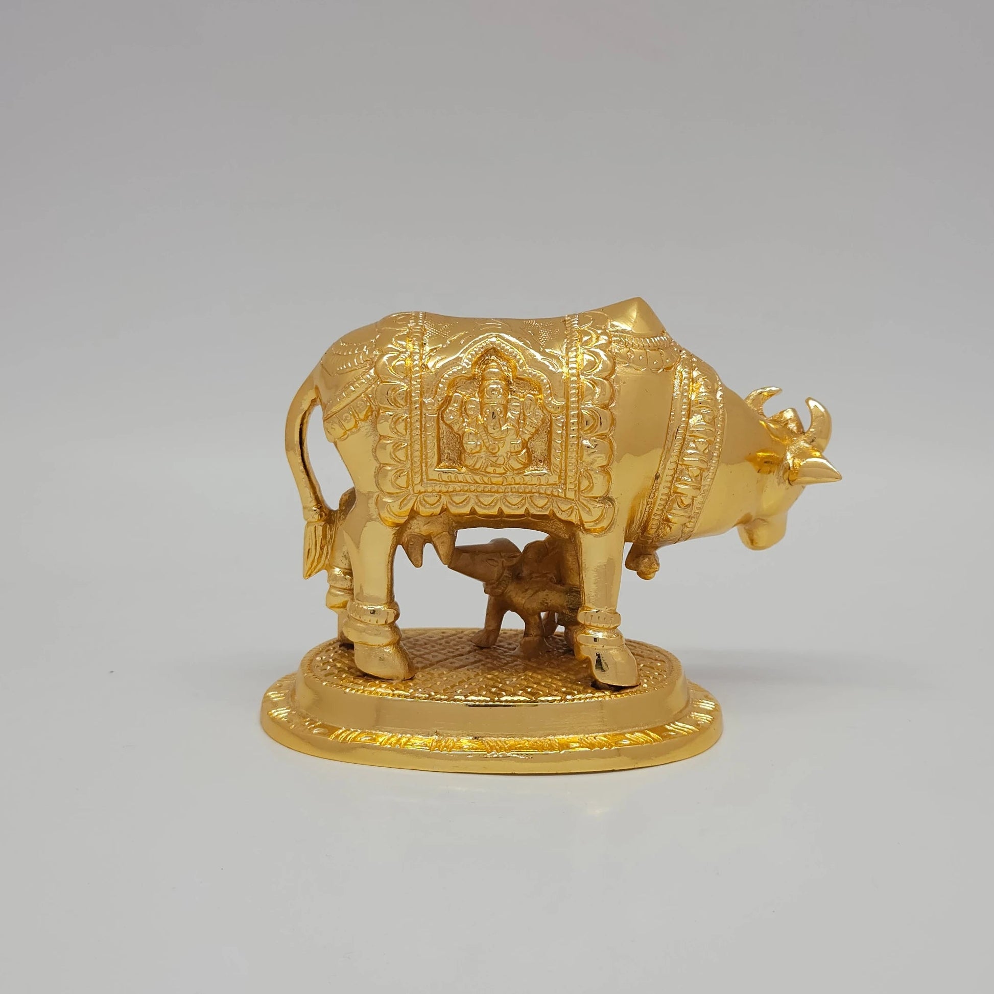 Sri Swaminathan and Co brass Kamadhenu cow and calf statue 1kg weight back pose full rear view showing reverse of polished tail and embossed Lord Ganesha inside temple arch