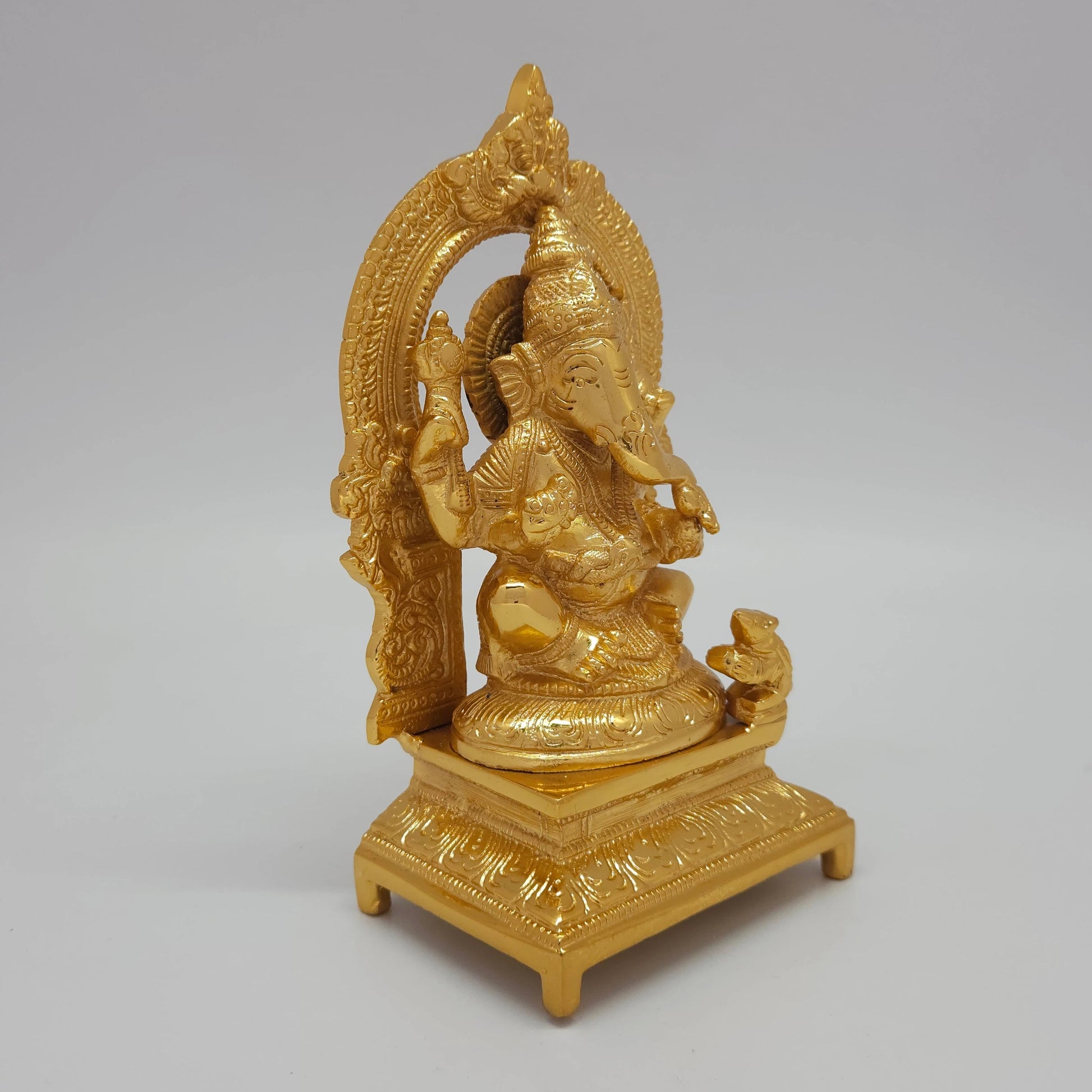 Sri Swaminathan and Co brass Ganesha statue with arch gold powder coated 7 inch 19cm height 45 degree right pose corner view focusing on mooshika mouse and base thickness
