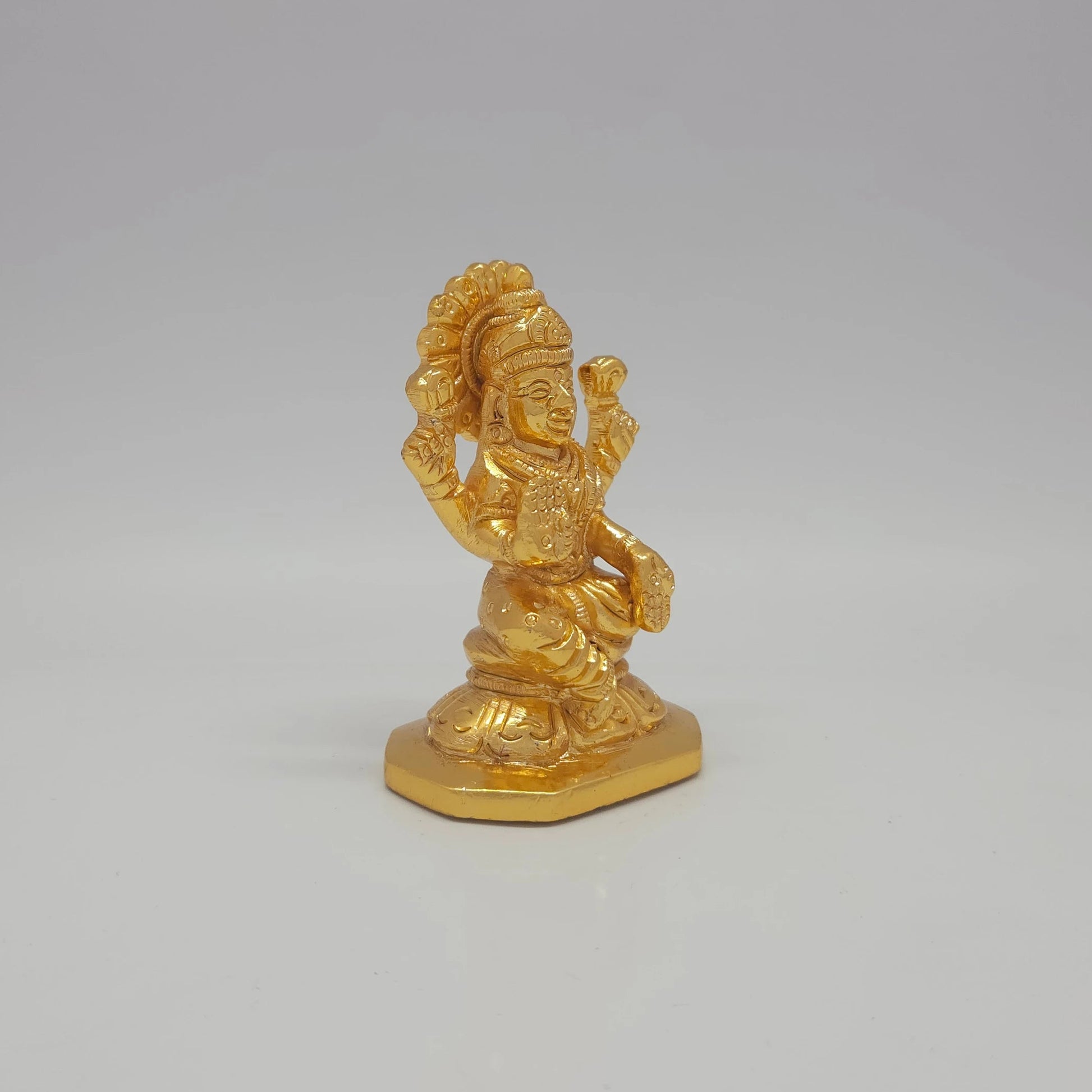 Sri Swaminathan and Co brass miniature Mahalakshmi statue gold finish 275g weight 45 degree right pose corner view focusing on protective abhaya mudra hand and octagonal base depth
