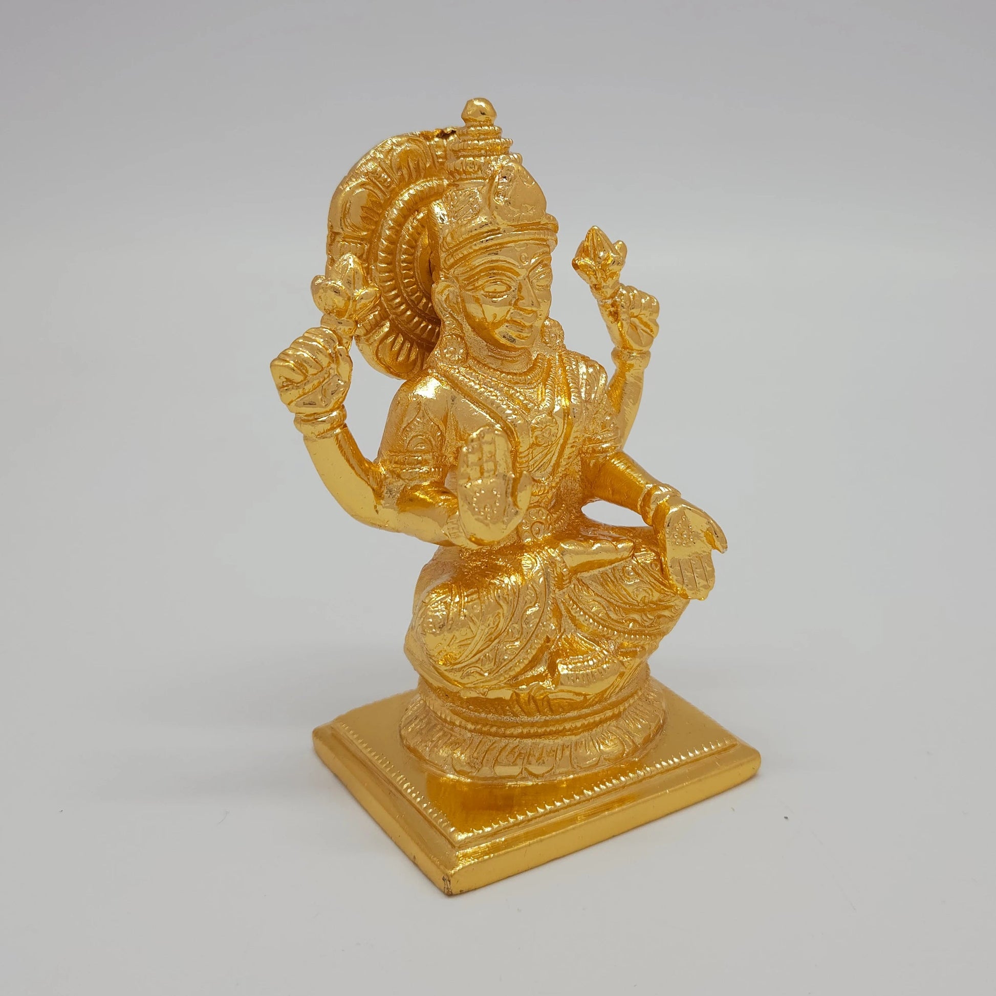 Sri Swaminathan and Co brass Lakshmi statue gold powder coated 4 inch 11cm height 45 degree right pose corner view focusing on varada mudra hand and base platform depth