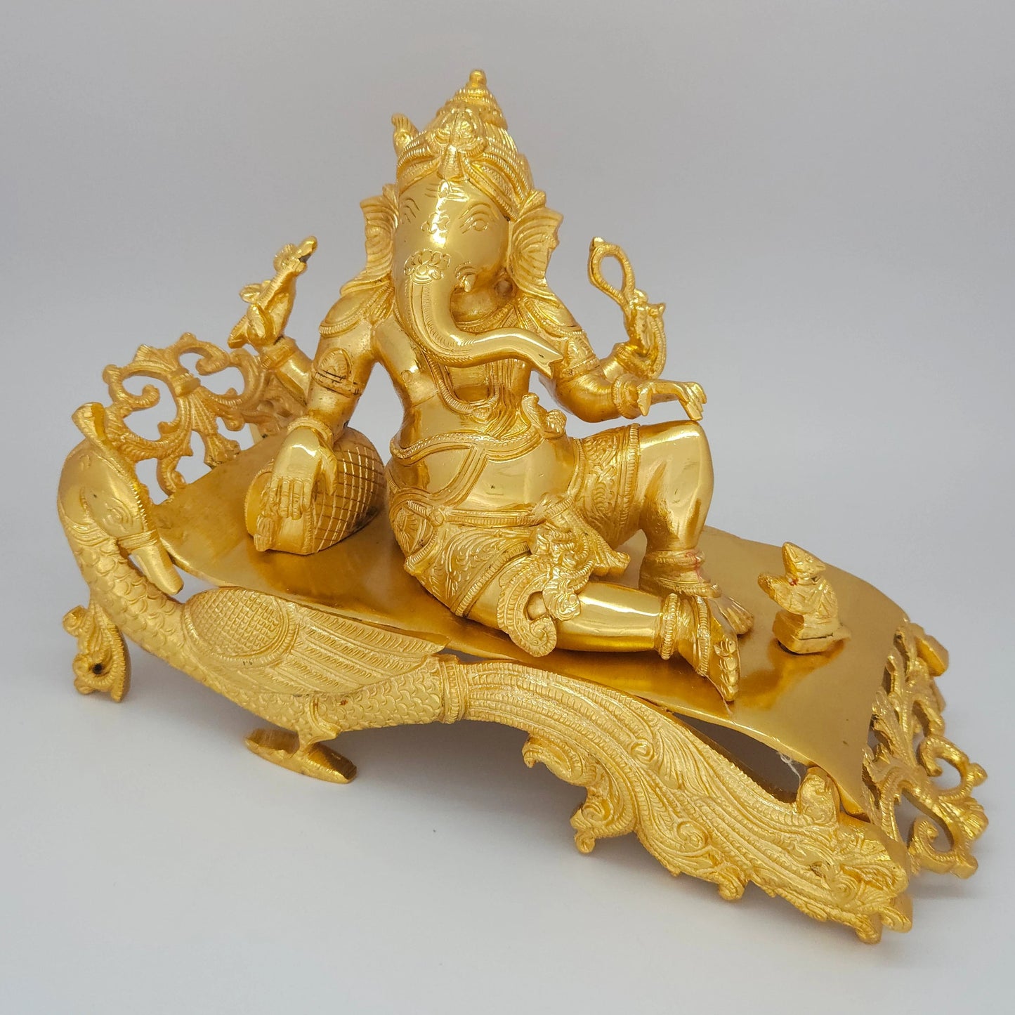 Sri Swaminathan and Co brass reclining Shayana Vinayaka statue gold finish 3.9kg weight 45 degree left pose corner view highlighting the chiseled peacock neck and bolster cushion details
